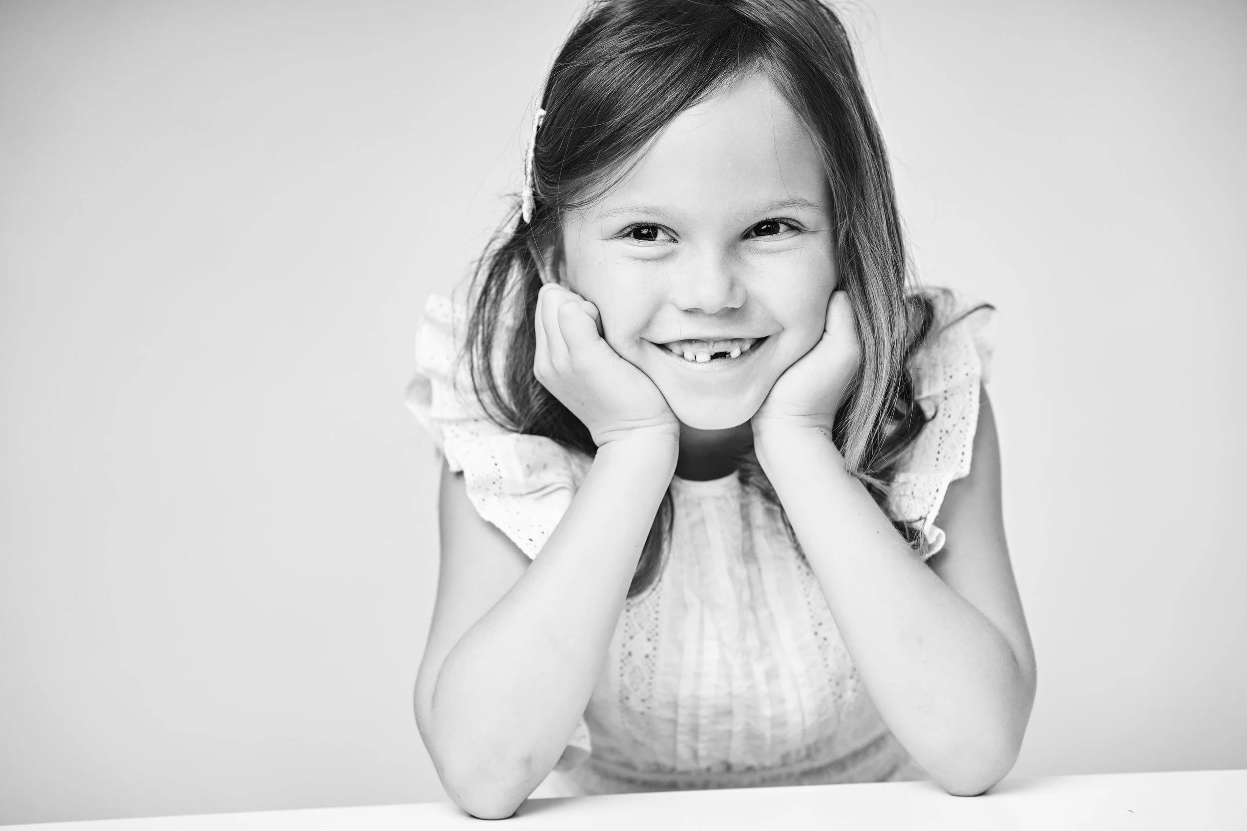 Elegant black and white children's studio portrait capturing a natural smile and joyful expression. Lucas Gudaniec Photography specialises in timeless children's and family portraits for clients across Annecy and Geneva.