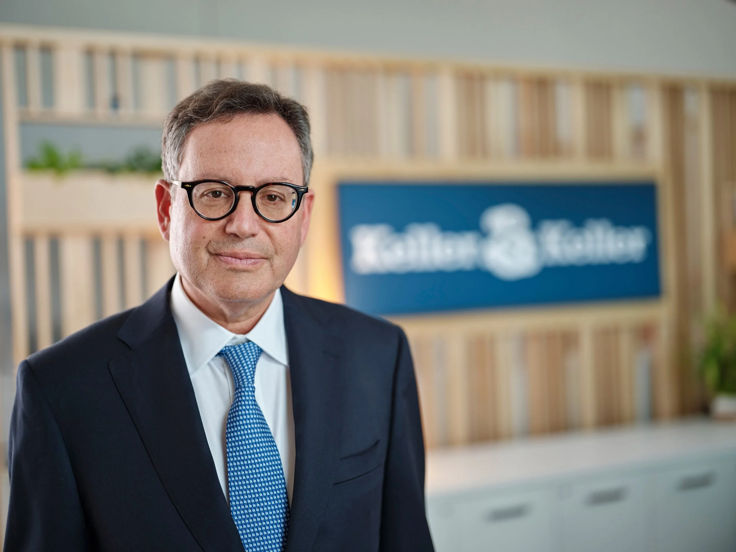 Lawyer Keller and Keller Businessman wearing glasses and a suit standing in a modern office