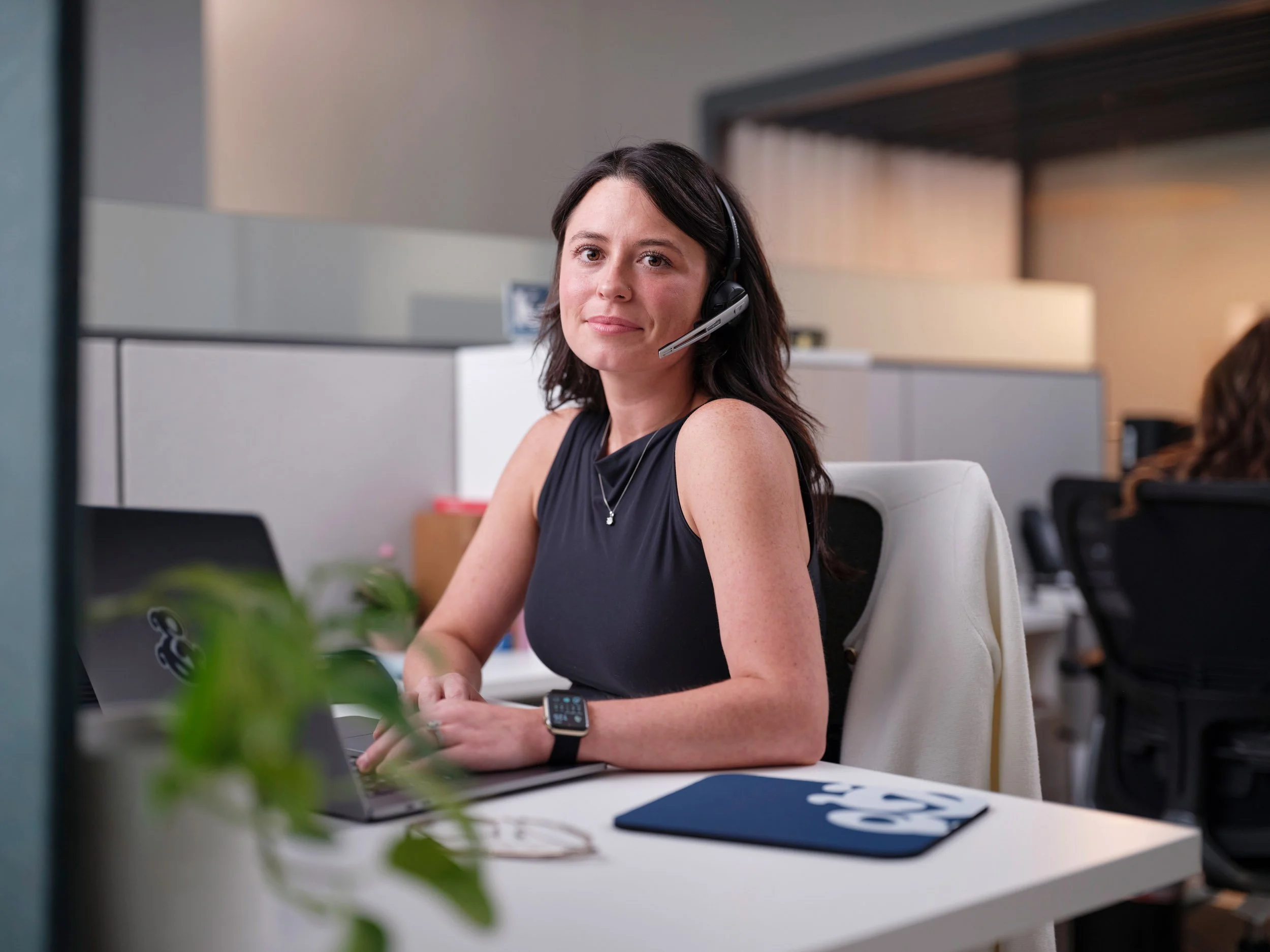 Woman wearing a headset working at a laptop in a modern office