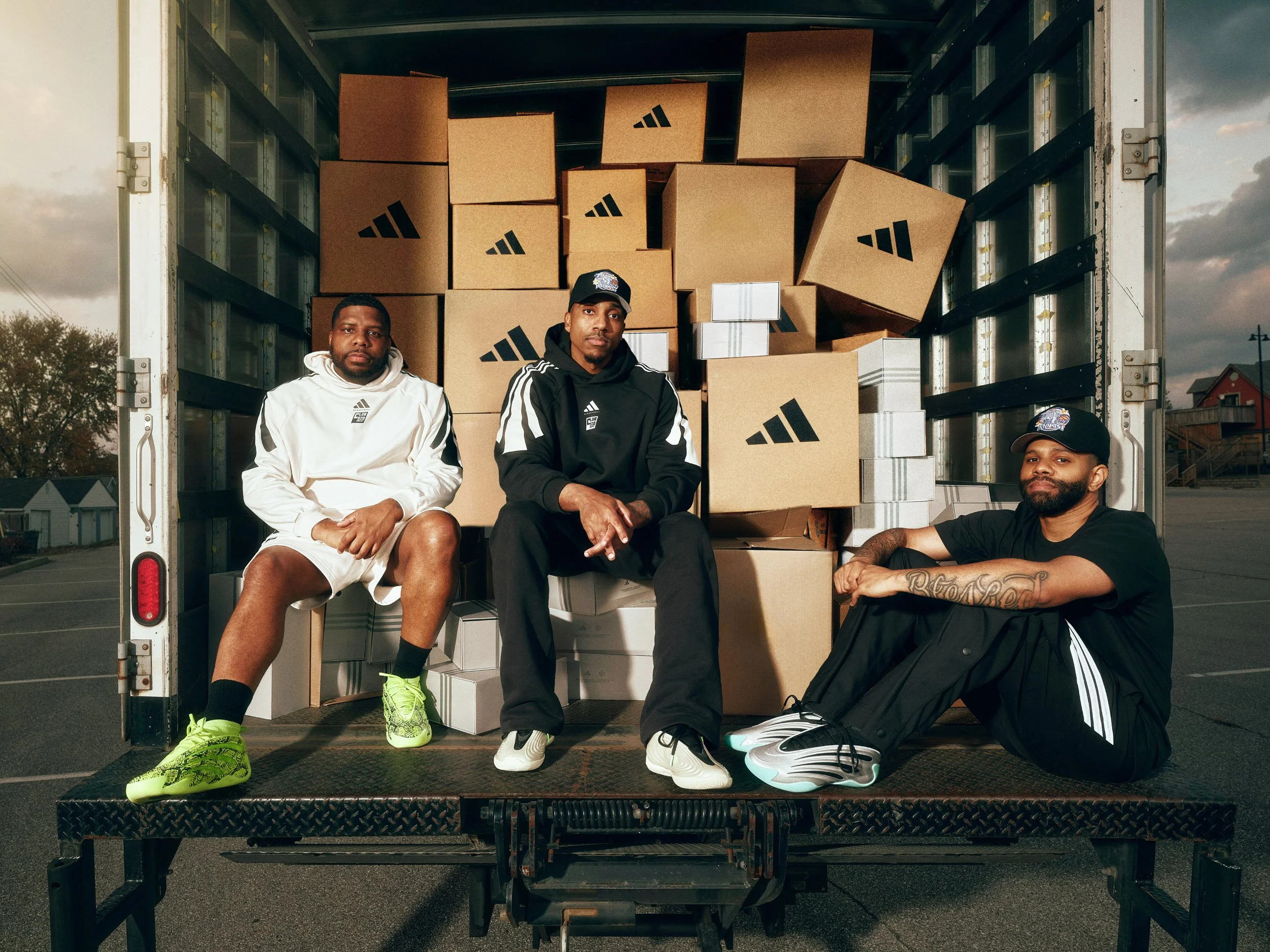 Club 520 Three men in Adidas clothing posed inside a moving truck filled with Adidas-branded cardboard boxes