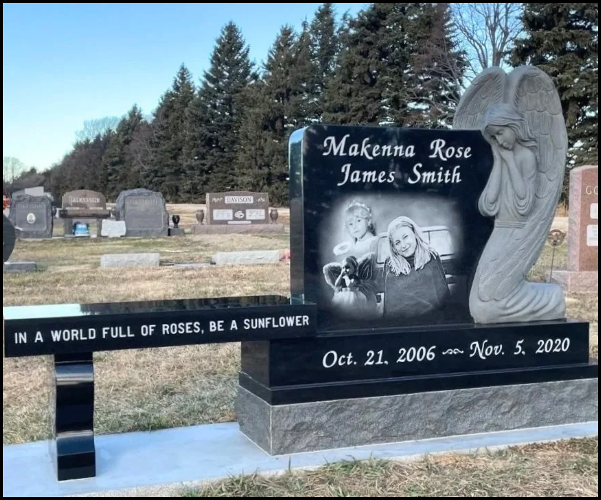 Black granite headstone with an angel sculpture on the right side. The headstone has engraved photos of two young girls, Makenna Rose and James Smith. The inscription includes their names and birth and death dates, October 21, 2006 to November 5, 2020. A black marble plaque in front displays the quote, 'In a world full of roses, be a sunflower'.