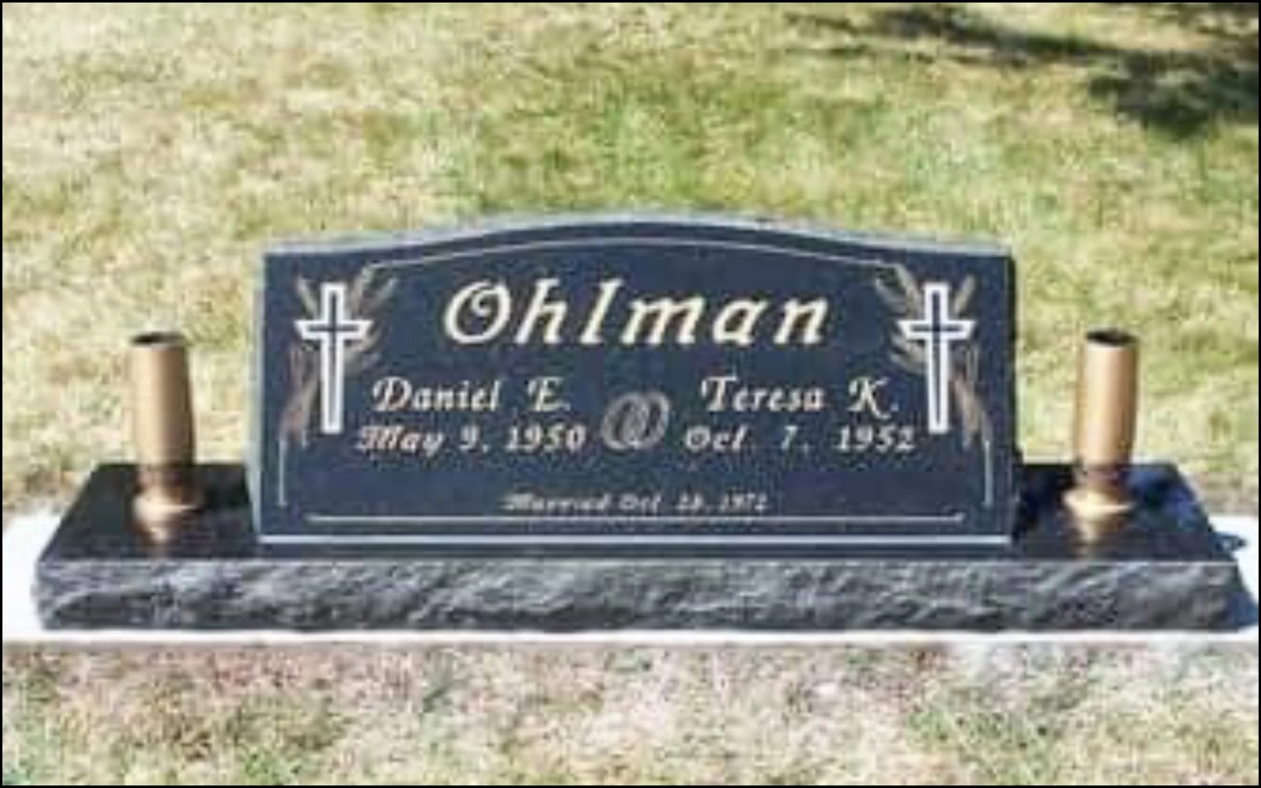 Gravestone with the name Ohlman, date of birth May 1, 1950, and date of death October 7, 1952, set in a grassy area with two small candles on either side.