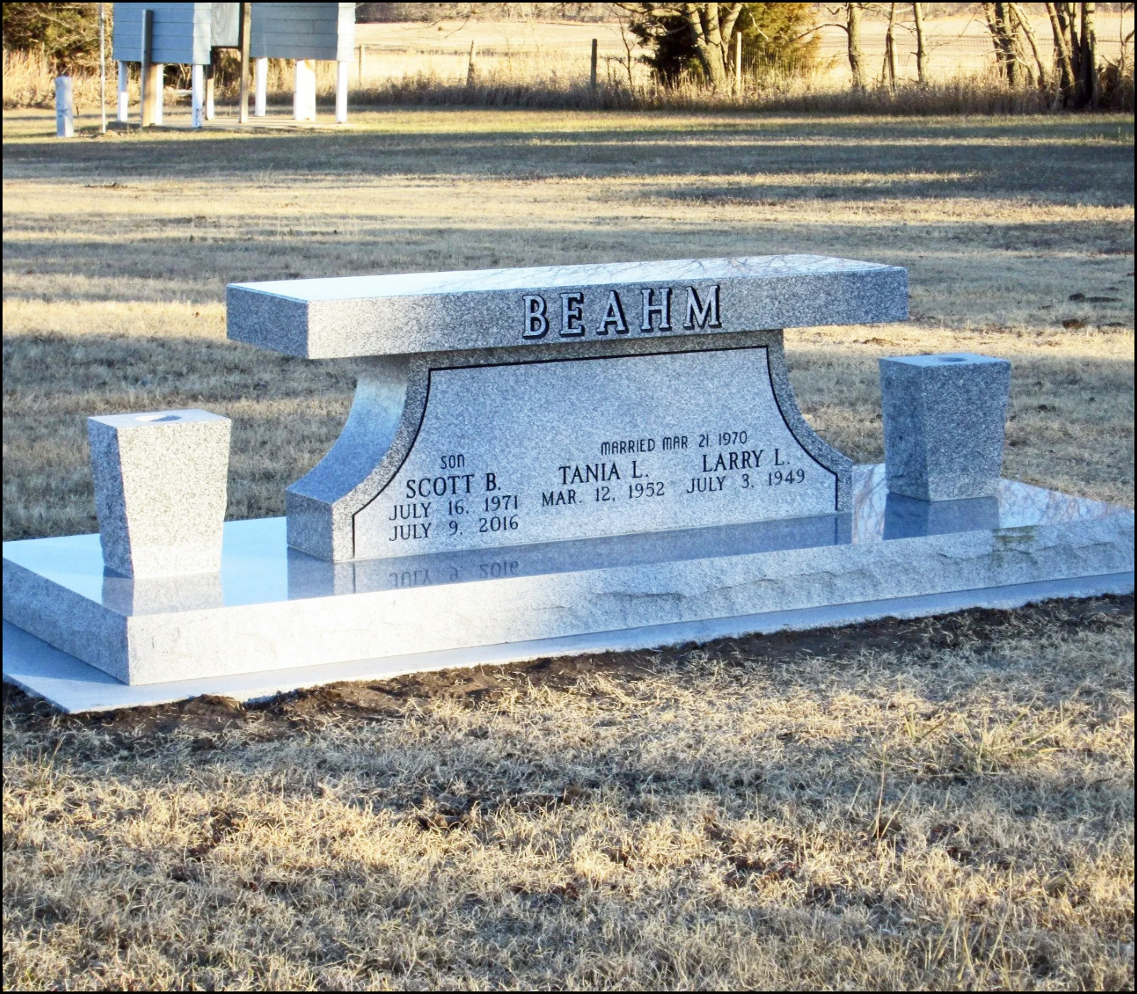 Gravestone with the surname BEAHM, dedicated to members of the Beahm family, including son Scott B., born July 16, 1971, died July 9, 2016, and parents Tania L. and Larry L., born March 12, 1952, and July 3, 1949, respectively, with an inscription of marriage date March 21, 1970, located outdoors in a grassy area with trees in the background.
