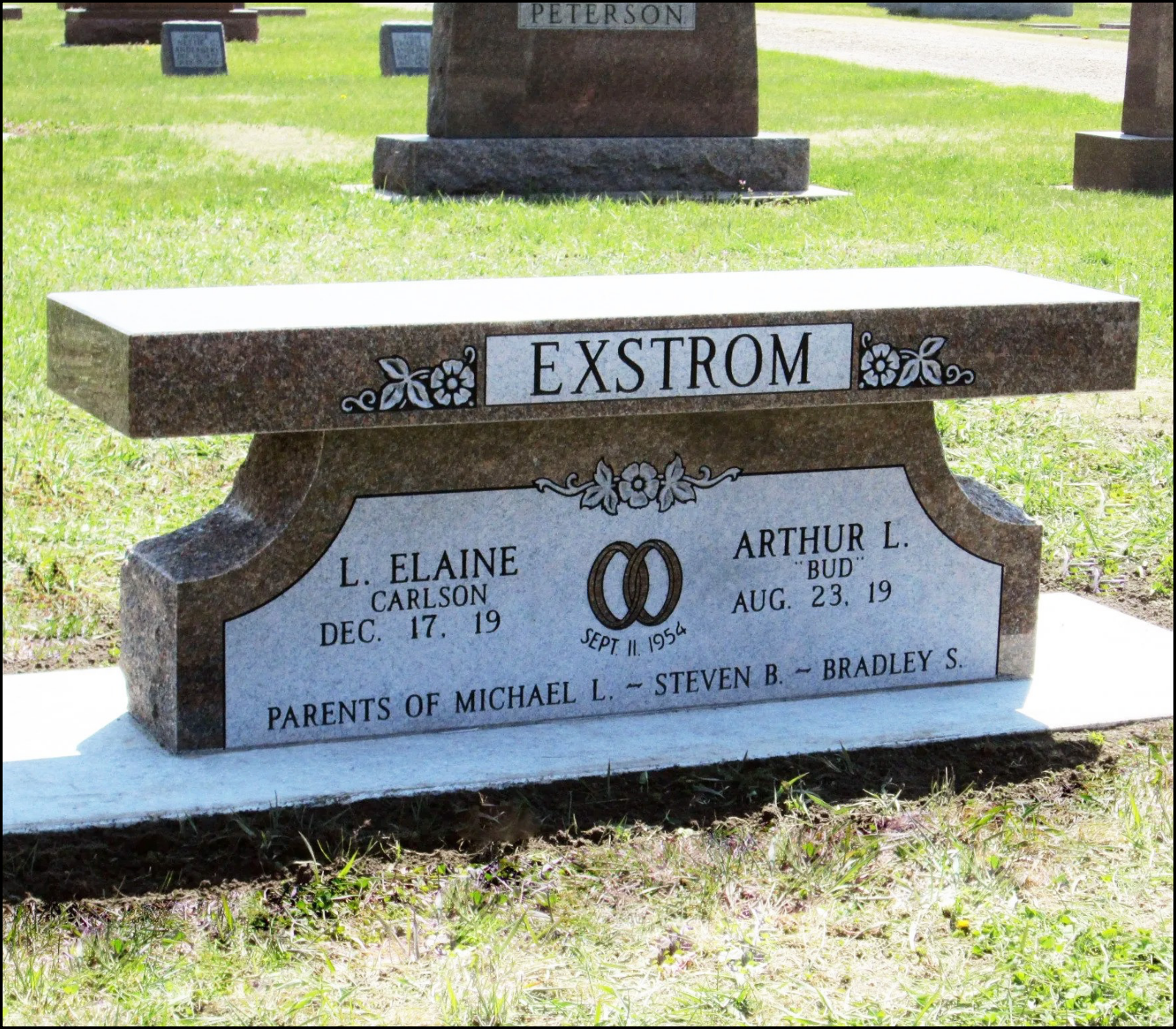 Gravestone with the name Extrem, in a cemetery with other gravestones in the background, and grass in the foreground.