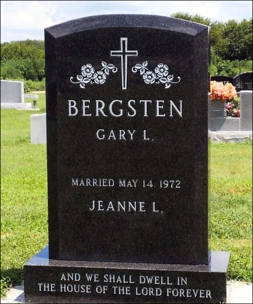 A black headstone with white engraved lettering and a cross with floral designs at the top. It displays the name Gary L. Bergsten, his marriage date May 14, 1972, and the name Jeanne L. The bottom of the headstone has a religious inscription, "And we shall dwell in the house of the Lord forever."