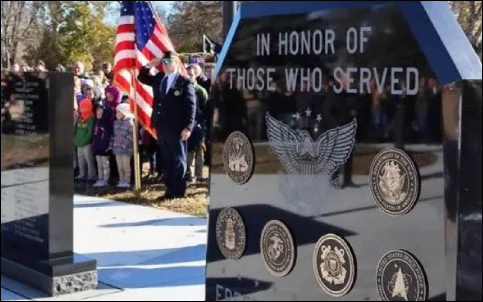 A memorial with the words 'In honor of those who served,' featuring military seals and a large angel emblem, with a group of people, including a man in a suit saluting and children holding a flags, gathered nearby at a cemetery.