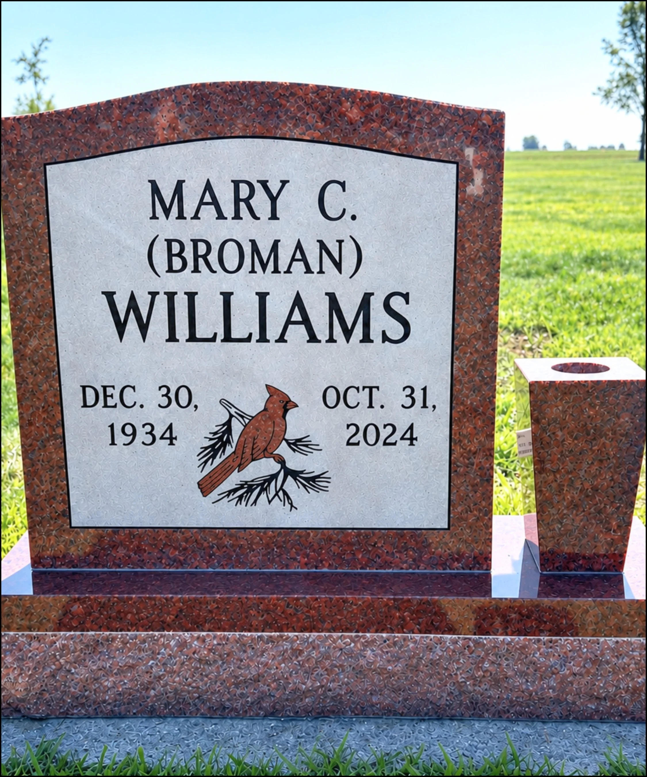Gravestone with the name Mary C. Broman Williams, birthdate December 30, 1934, and death date October 31, 2024, surrounded by greenery, with a matching stand nearby.