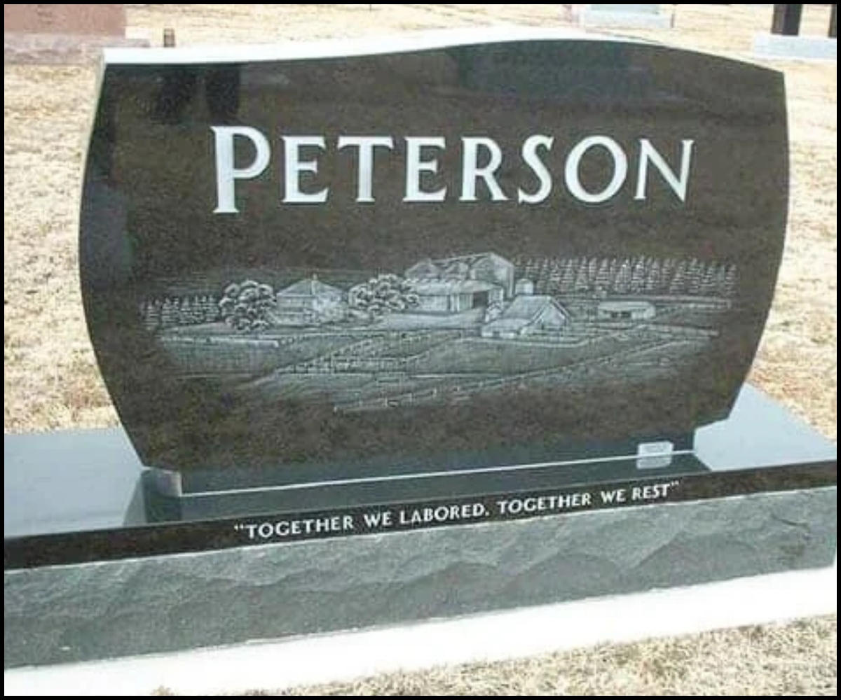 A black granite headstone with the name "Peterson" and an engraved landscape of houses and trees. The inscription at the bottom reads "Together we labored. Together we rest."