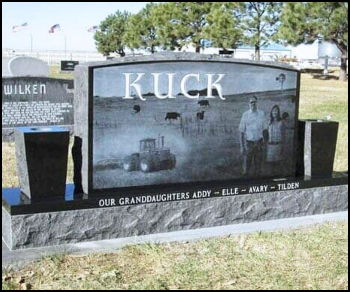 A gravestone with the name 'Kuck' engraved at the top, featuring a farm scene with cows and a tractor in the background. The gravestone has a black and gray color theme. There is a side plaque with a dedication to granddaughters Elle, Amy, and Tilden.