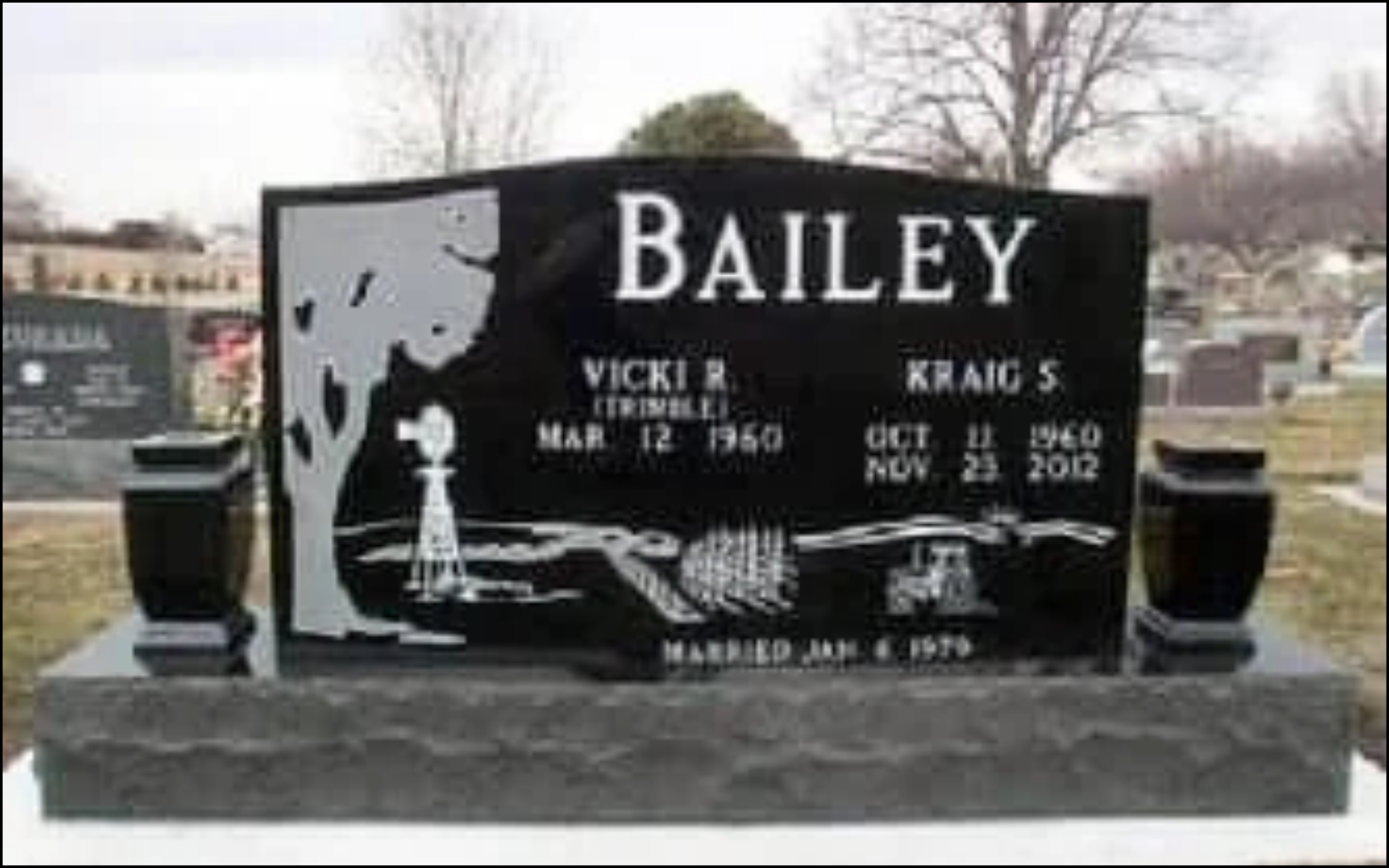Black and white gravestone with a portrait and inscription for Bailey, Vicki R. and Craig S., with birth and death dates, in a cemetery with trees and other headstones in the background.