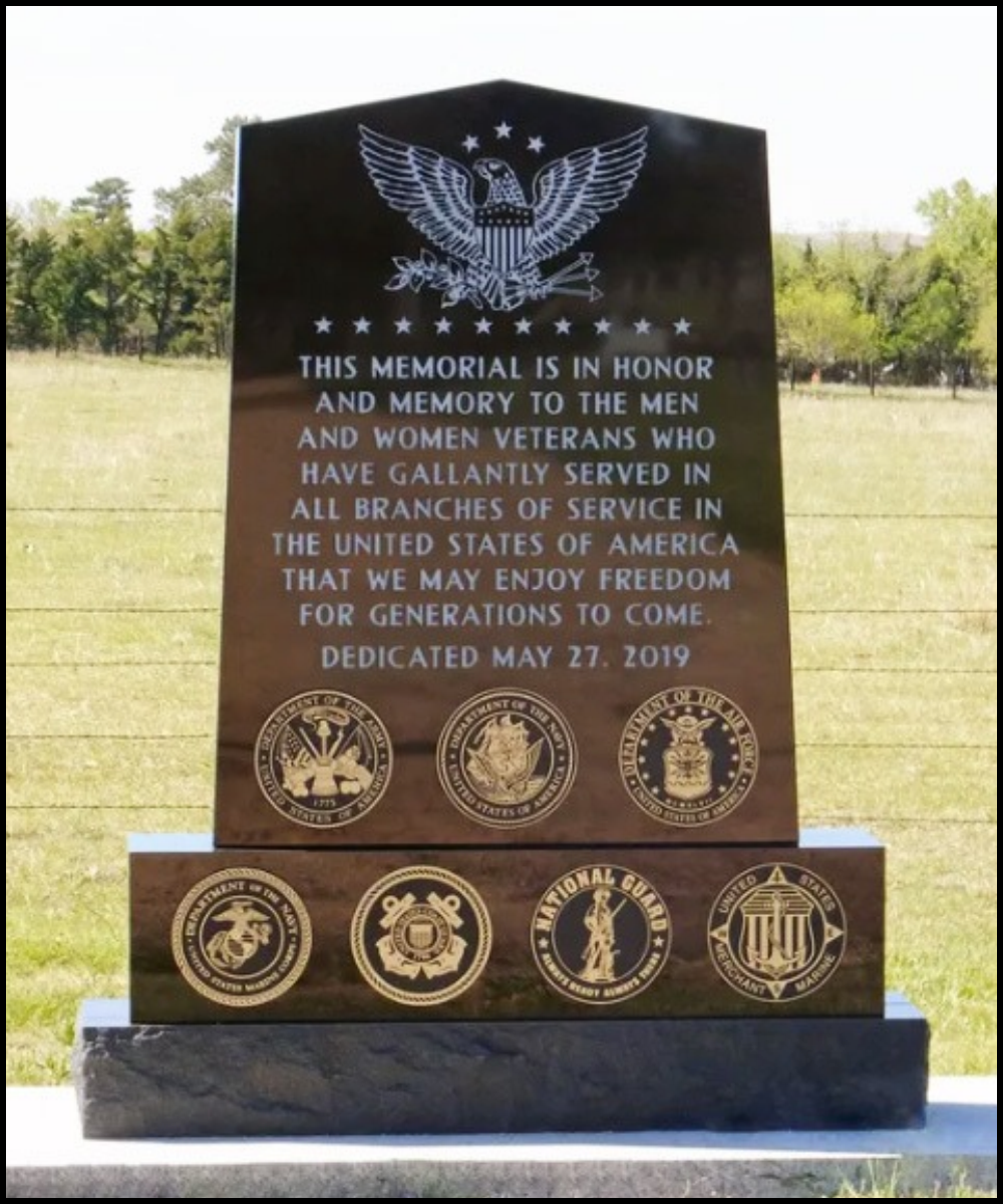 A memorial monument dedicated to U.S. veterans, featuring an eagle with outstretched wings at the top and portraits of various military service branches at the bottom. The inscription honors men and women veterans, with a dedication date of May 27, 2019.