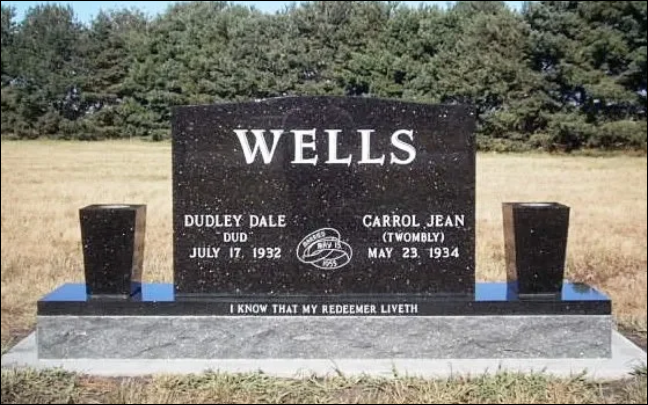 A black granite headstone in a grassy outdoor cemetery, commemorating Dudley Dale and Carroll Jean Wells, with dates of birth and death, and an inscription at the bottom.