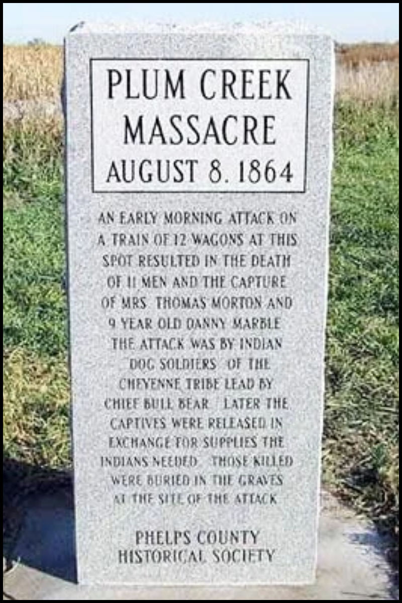 A historical monument stone memorial commemorating the Plum Creek Massacre on August 8, 1864, describing an early morning attack on a train of 12 wagons by Indian dog soldiers of the Cheyenne tribe, resulting in deaths of 11 men and the capture of Mrs. Thomas Morton and a 9-year-old boy, with some bodies buried at the site.