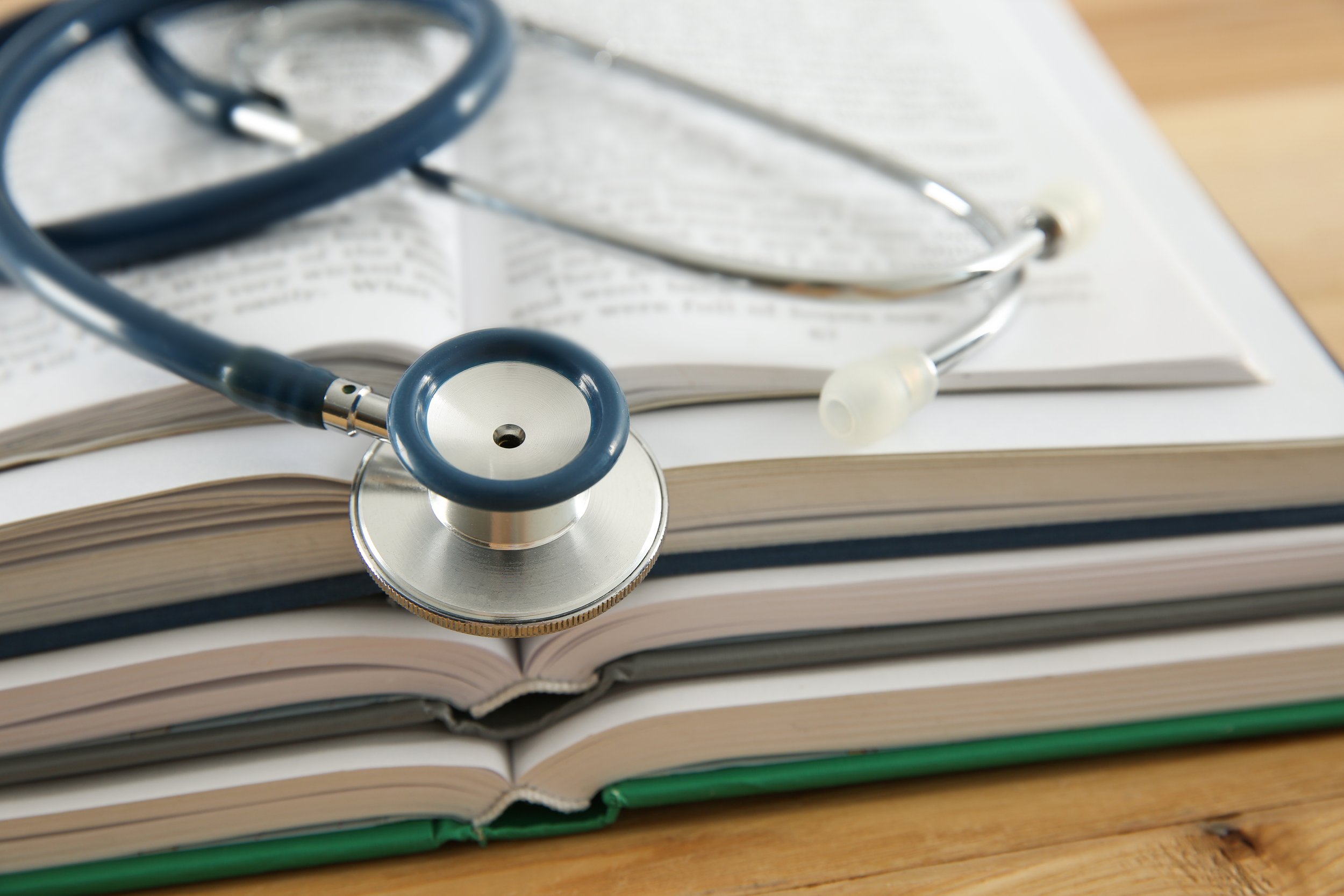 A stethoscope resting on open medical books with text visible on the pages.