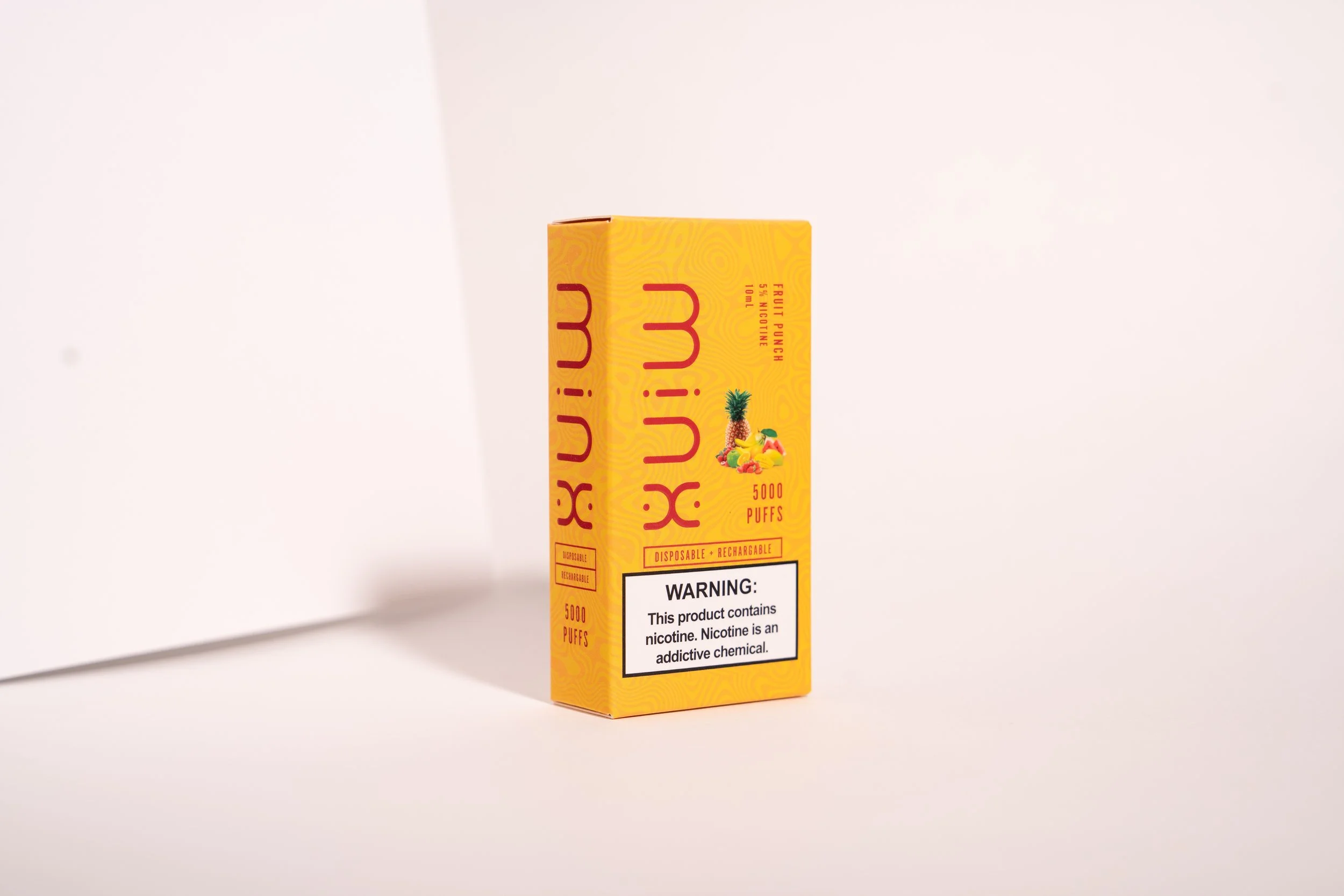 Yellow box of MiX disposable vape with pineapple, mango, and fruit illustrations, indicating flavor, and a warning label about nicotine content on a light background.