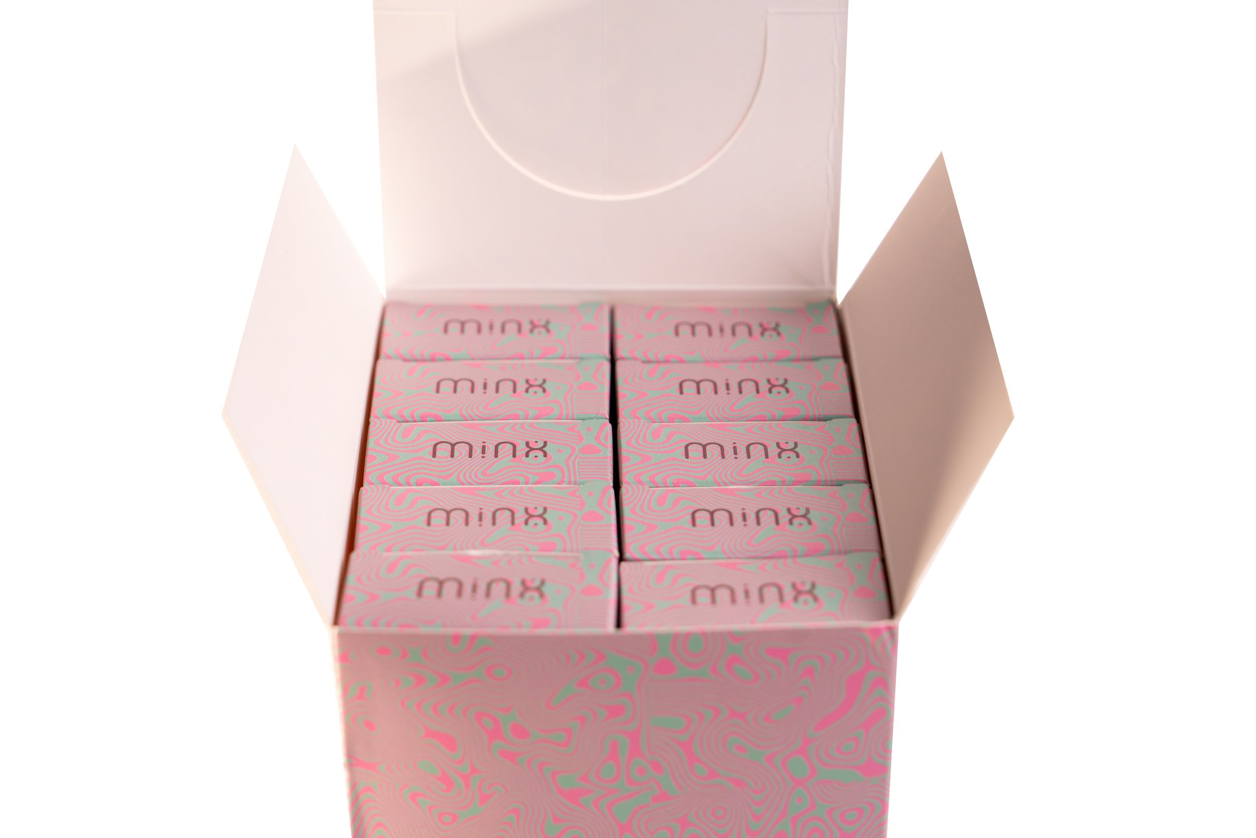 Open pink and white box containing small boxes labeled 'minx' with abstract swirl patterns.
