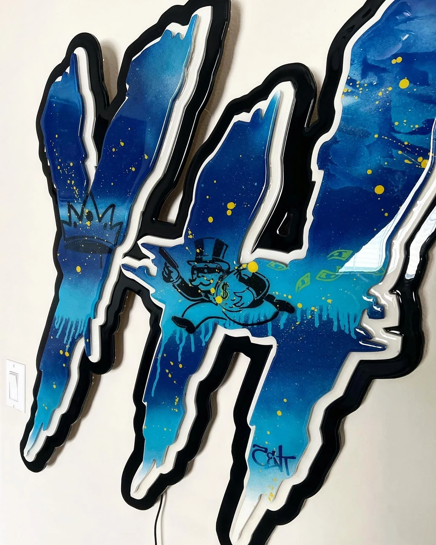Colorful neon sign featuring a blue and yellow cosmic background with a cartoon money bag wearing a top hat, holding a gun, and surrounded by dollar bills, outlined in black and white.