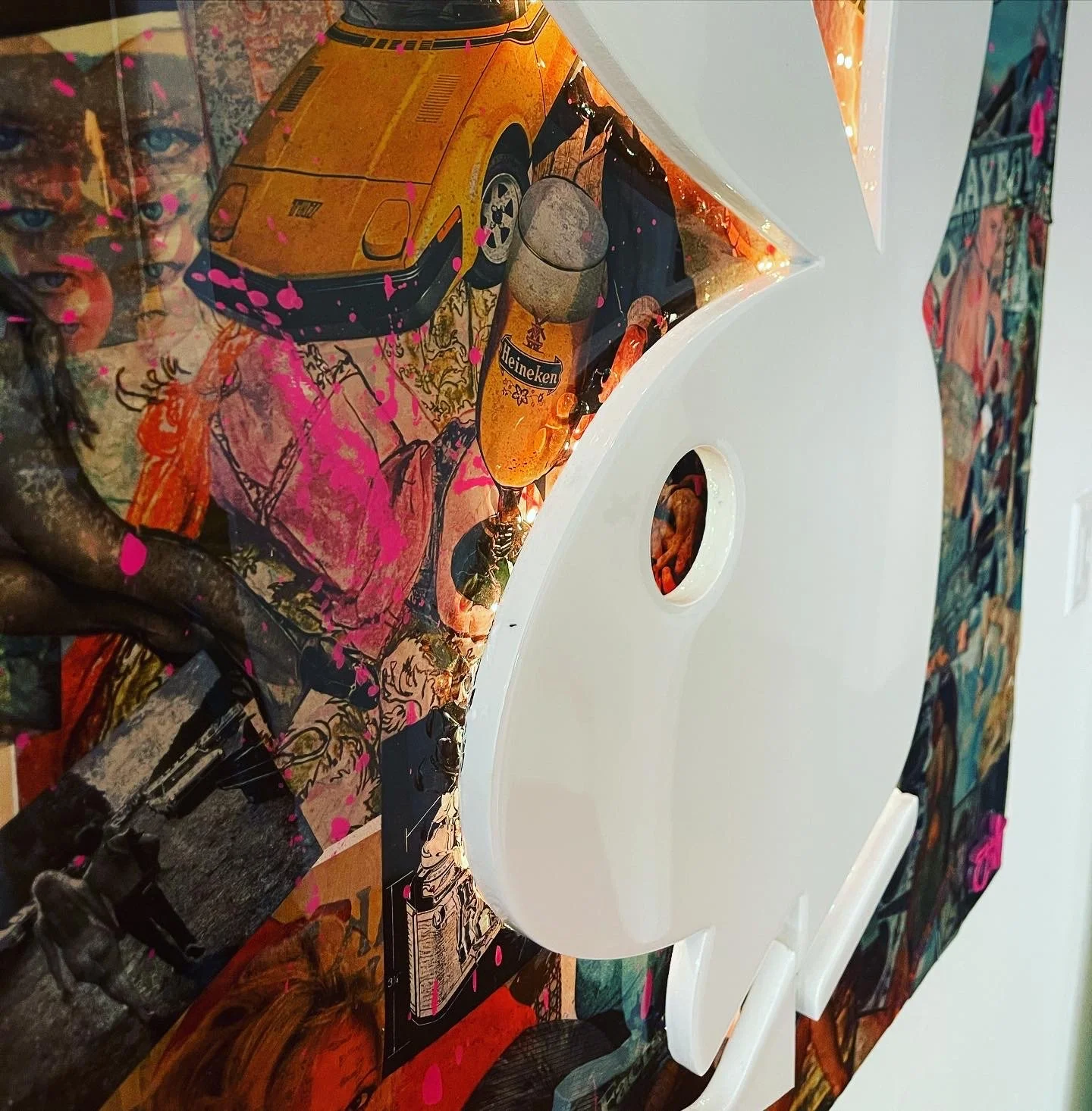 Close-up of a colorful, abstract collage featuring a yellow sports car, a glass of beer, and overlapping artwork, with a large white decorative element in the foreground.