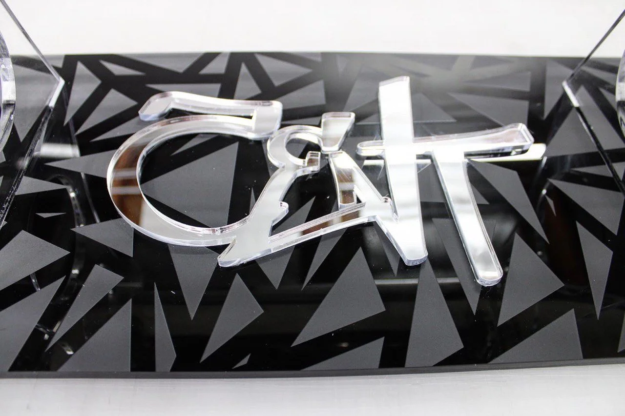 Close-up of the word 'craft' spelled out with acrylic letters on a black surface with geometric patterns.