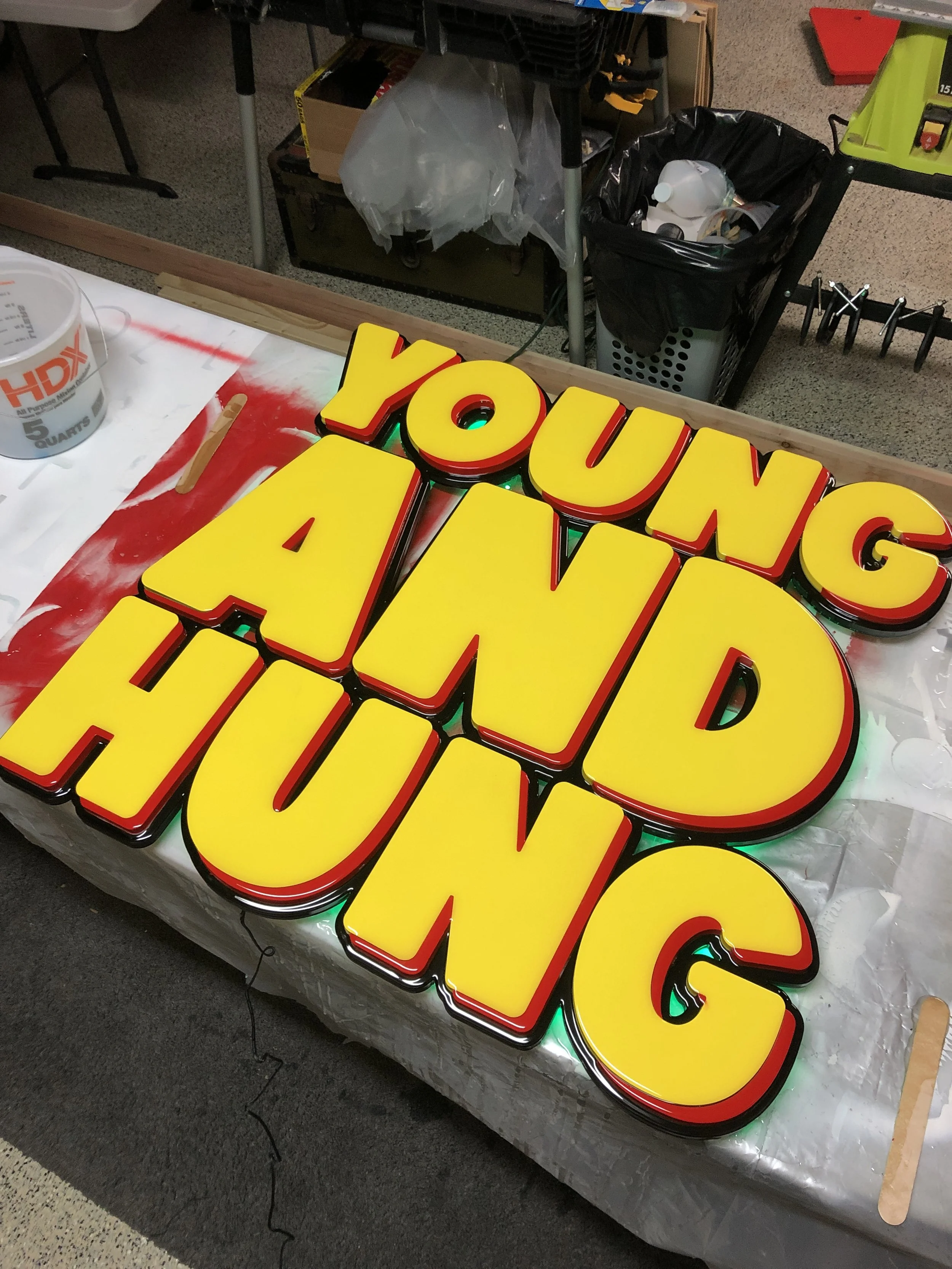 Colorful illuminated sign reading 'YOUNG AND HUNGRY' on a work table.