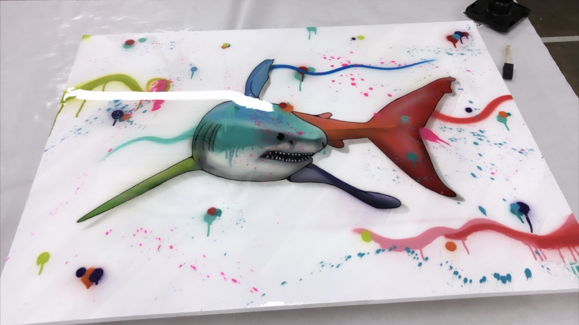 Colorful abstract artwork of a shark and a fish on a white background with paint splatters.