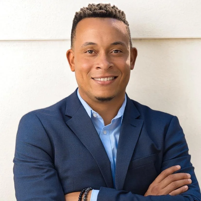 Tony Grant, founder of Grant Strategic Communications, wearing a navy blue suit and smiling with his arms crossed.