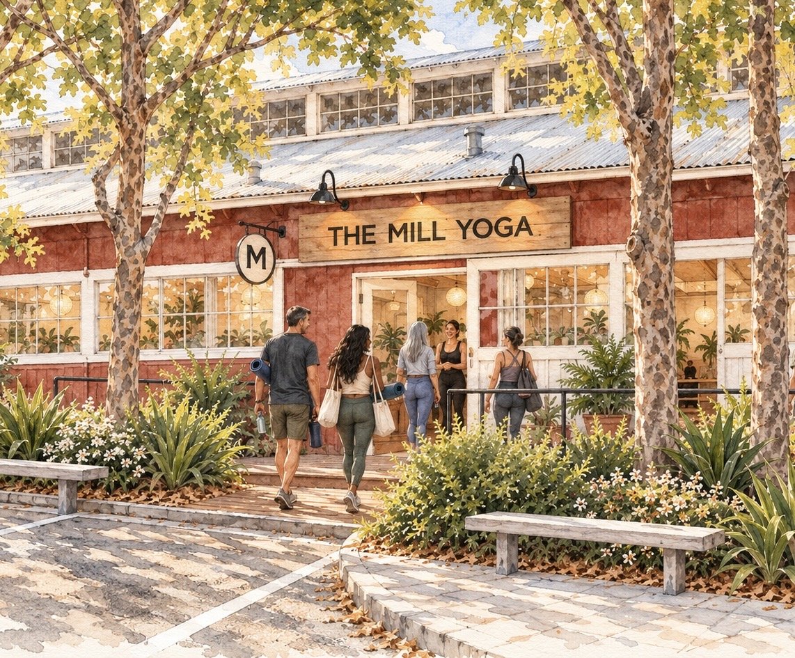 People entering The Mill Yoga studio in a small outdoor shopping area with trees, plants, and benches.