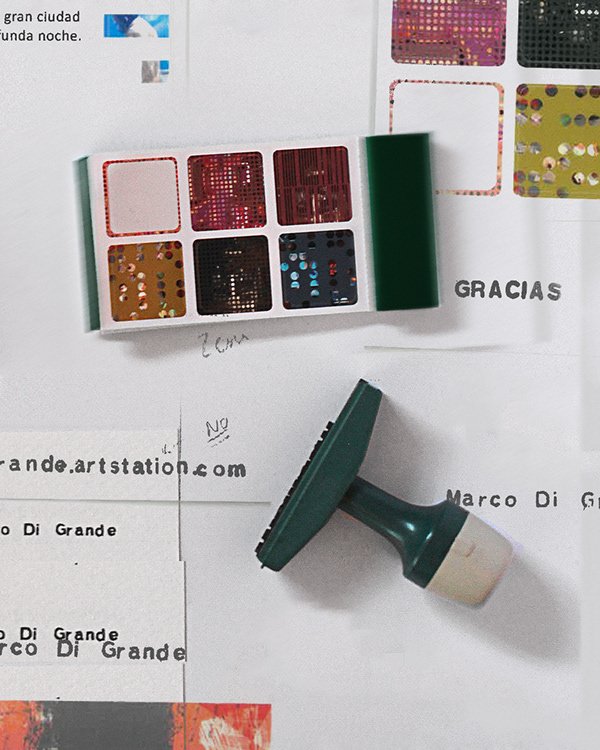 Close-up of a stamp pad and a sheet of paper with colorful square stamps or stickers, some partially visible, and handwritten notes.