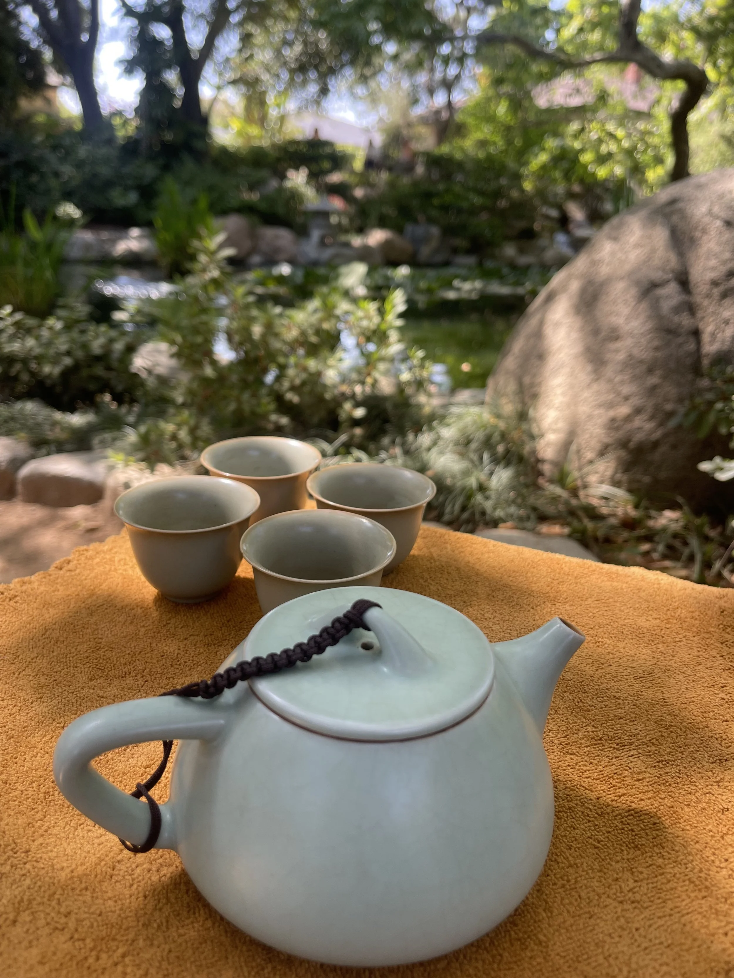 a teapot and cups, with a tea garden in the background