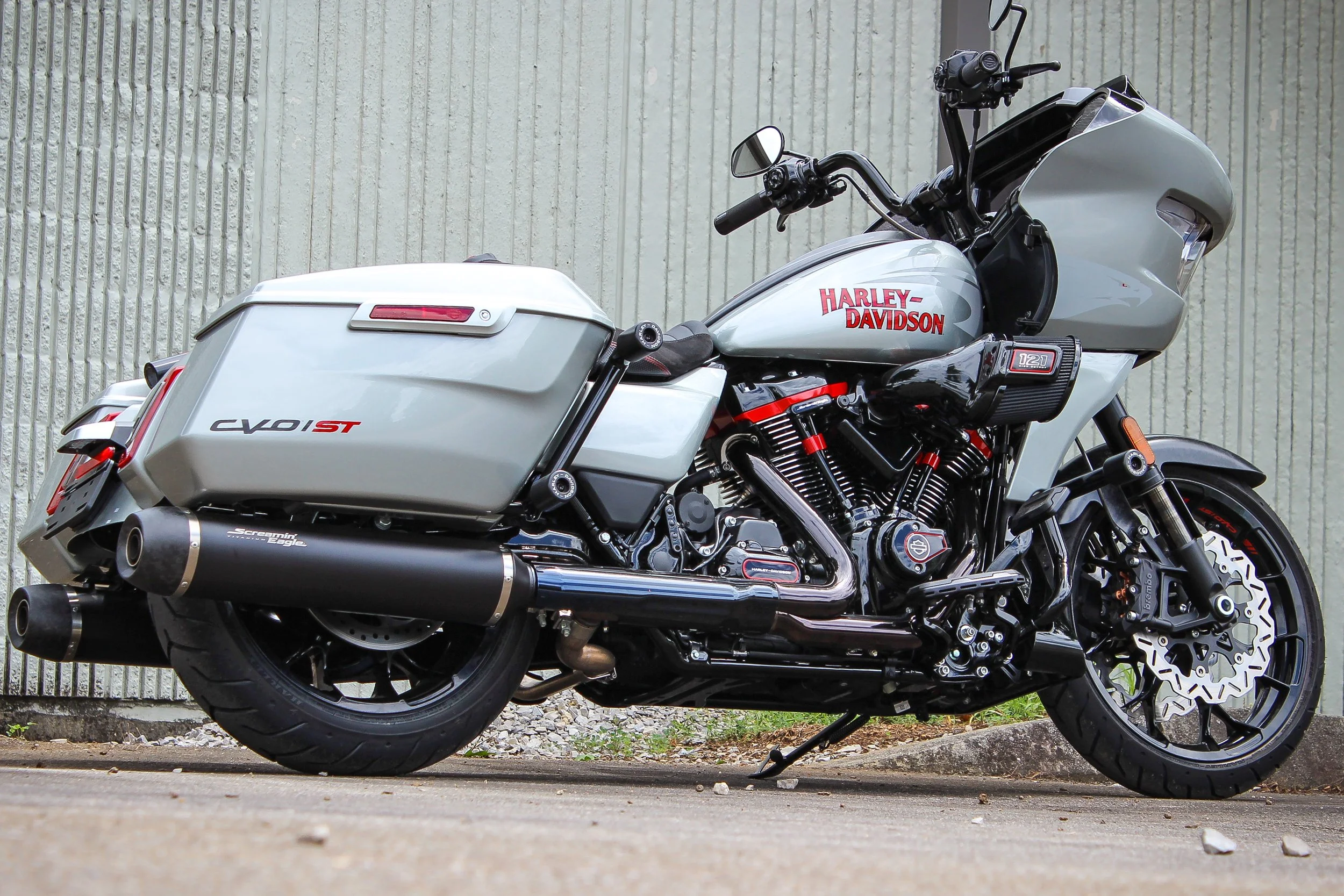 A Harley-Davidson motorcycle parked on a concrete surface in front of a textured wall, featuring a large front fairing, saddlebags, black and silver color scheme, and chrome accents.