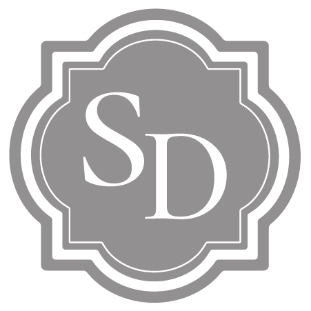 Gray and white logo with the letters 'SD' in the center, surrounded by a decorative border.