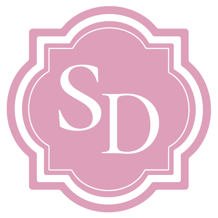 Pink decorative emblem with the initials 'SD' in white.