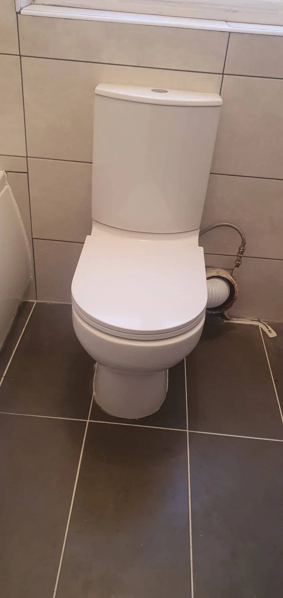White ceramic toilet in a tiled bathroom