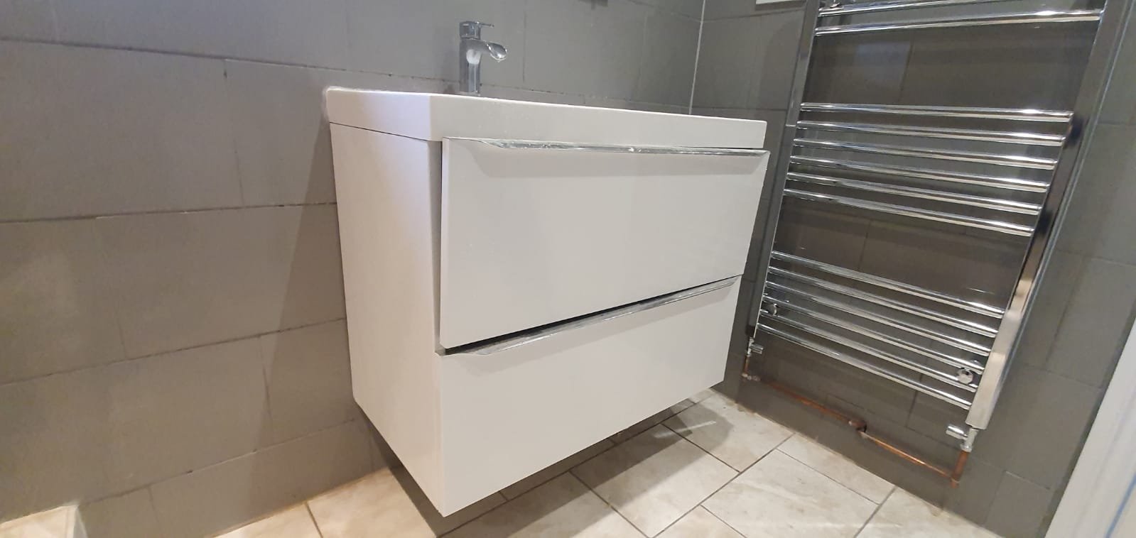 Modern white bathroom vanity with sink and chrome heated towel rail