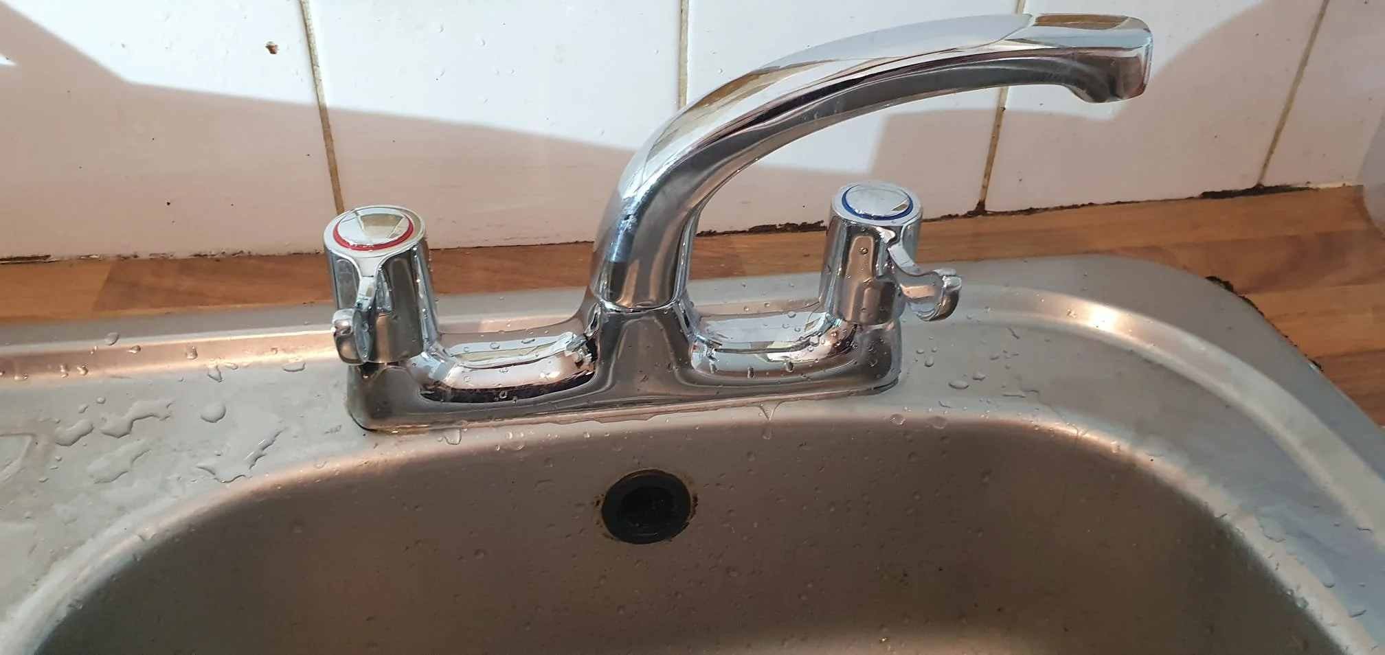 Chrome two-handle kitchen faucet mounted on a stainless steel sink