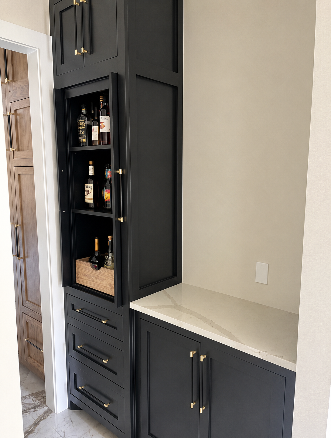 Custom black kitchen cabinetry with gold handles, glass doors, showcasing modern cabinet design.