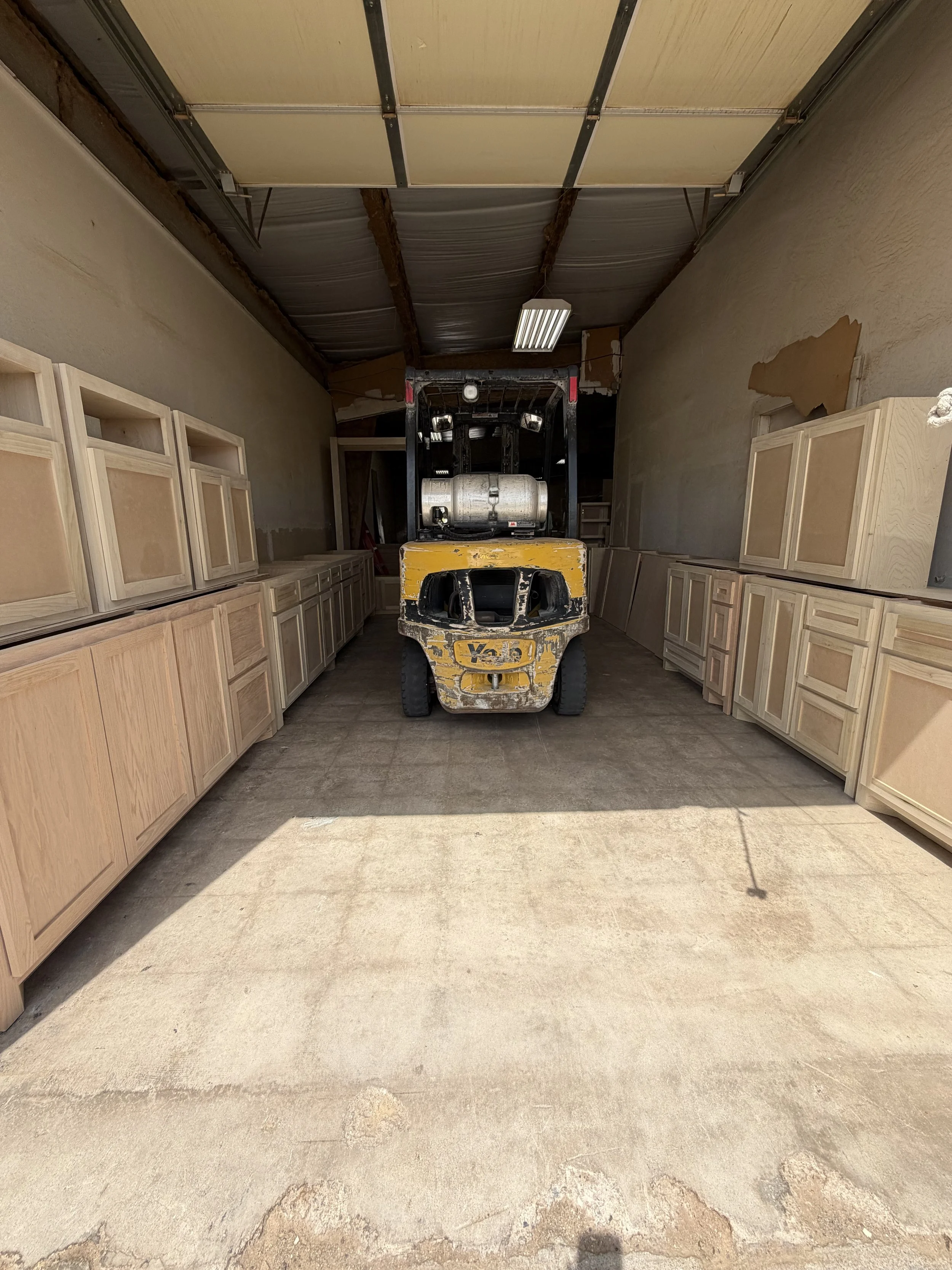 Custom Cabinet shop with a yellow forklift in the center, surrounded by custom cabinets along the wall.
