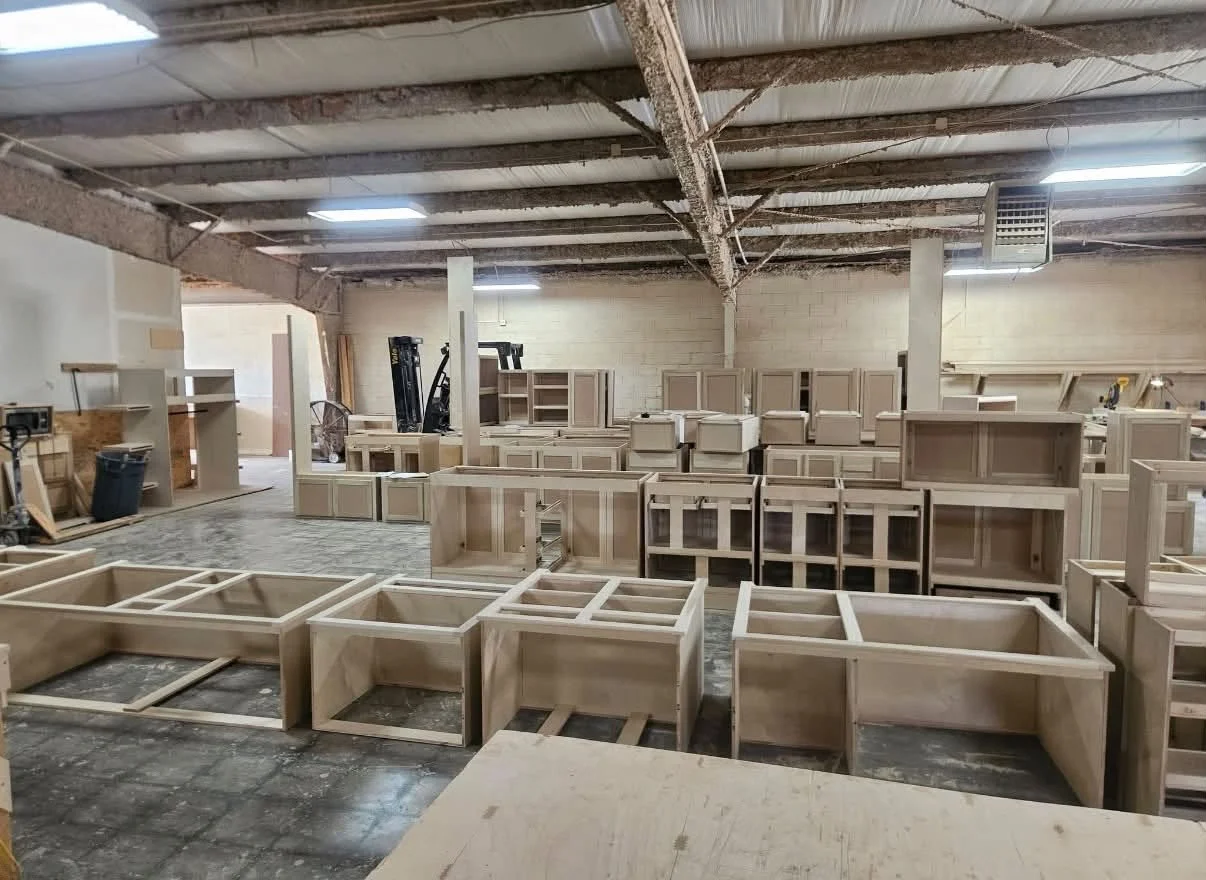 Rows of unfinished plywood cabinet boxes and assemblies inside Advantage Carpentry's cabinet manufacturing shop in Midwest City, Oklahoma.