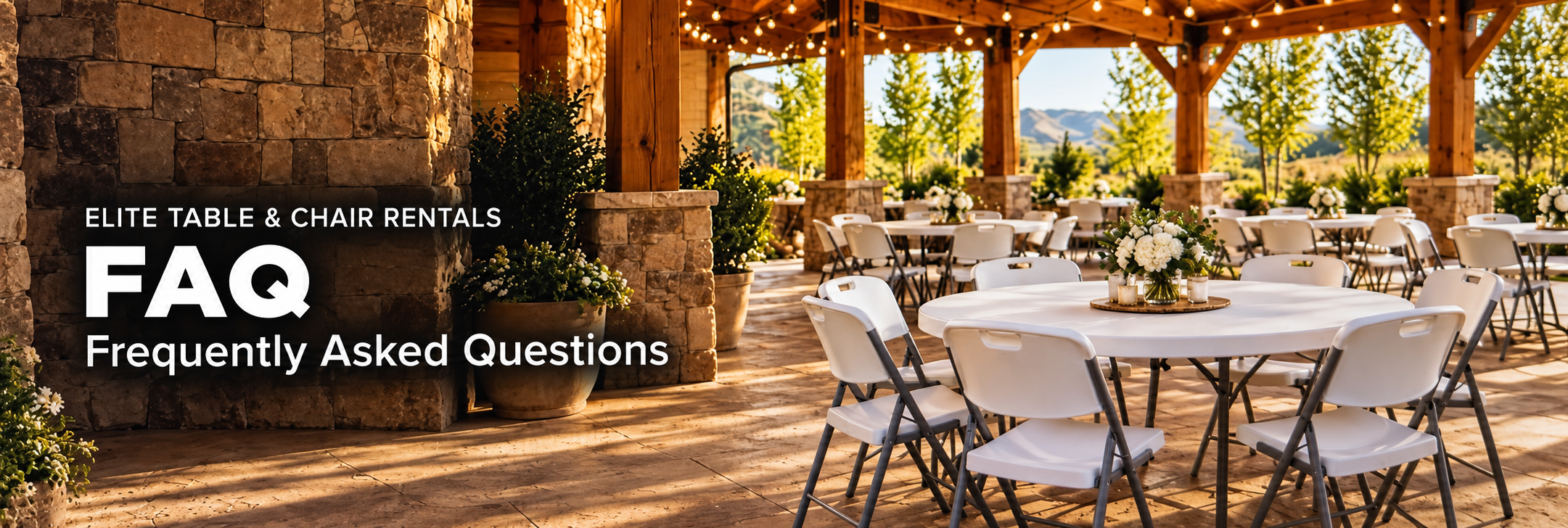 An outdoor event space with round tables and white chairs, decorated with floral centerpieces, under a wooden canopy with string lights and surrounded by trees and mountains.