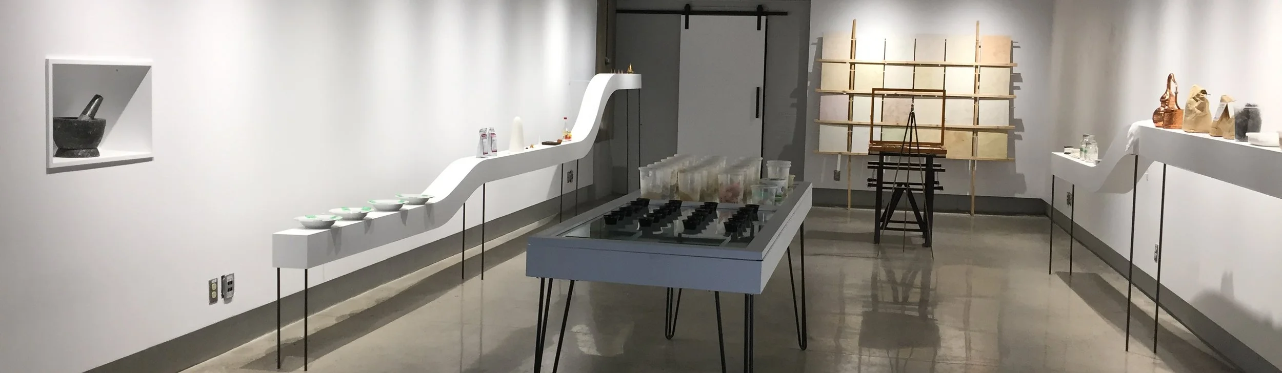 PLATE 2.28: Dürer’s Nose exhibition including the fragrant wall panels (right rear wall) along with the lime plaster pigments and plaster samples (center table), tools and materials (placed on “fragrance tables” and in niche at the far left and far r