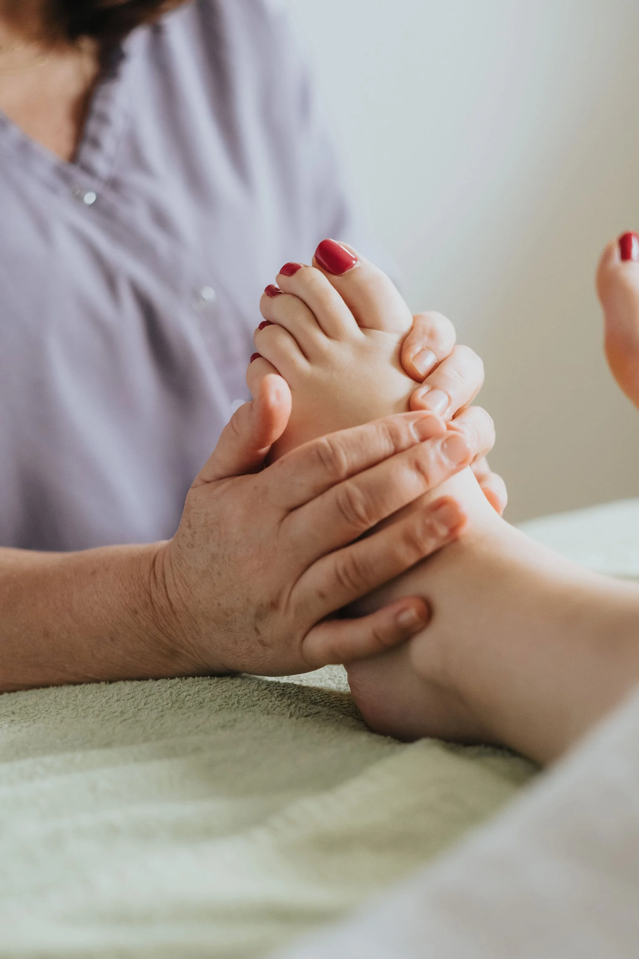 Massage du pied d'une cliente, en réflexologie plantaire.