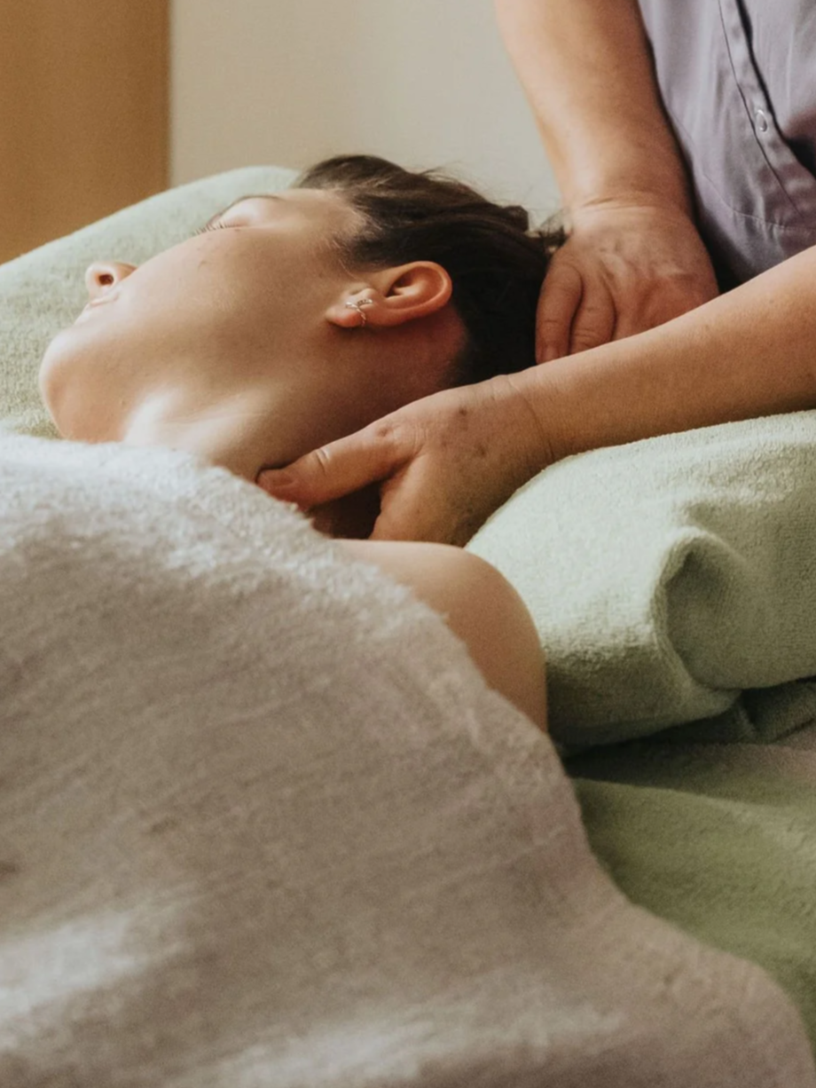 Massage de la nuque et du cou d'une femme allongée.