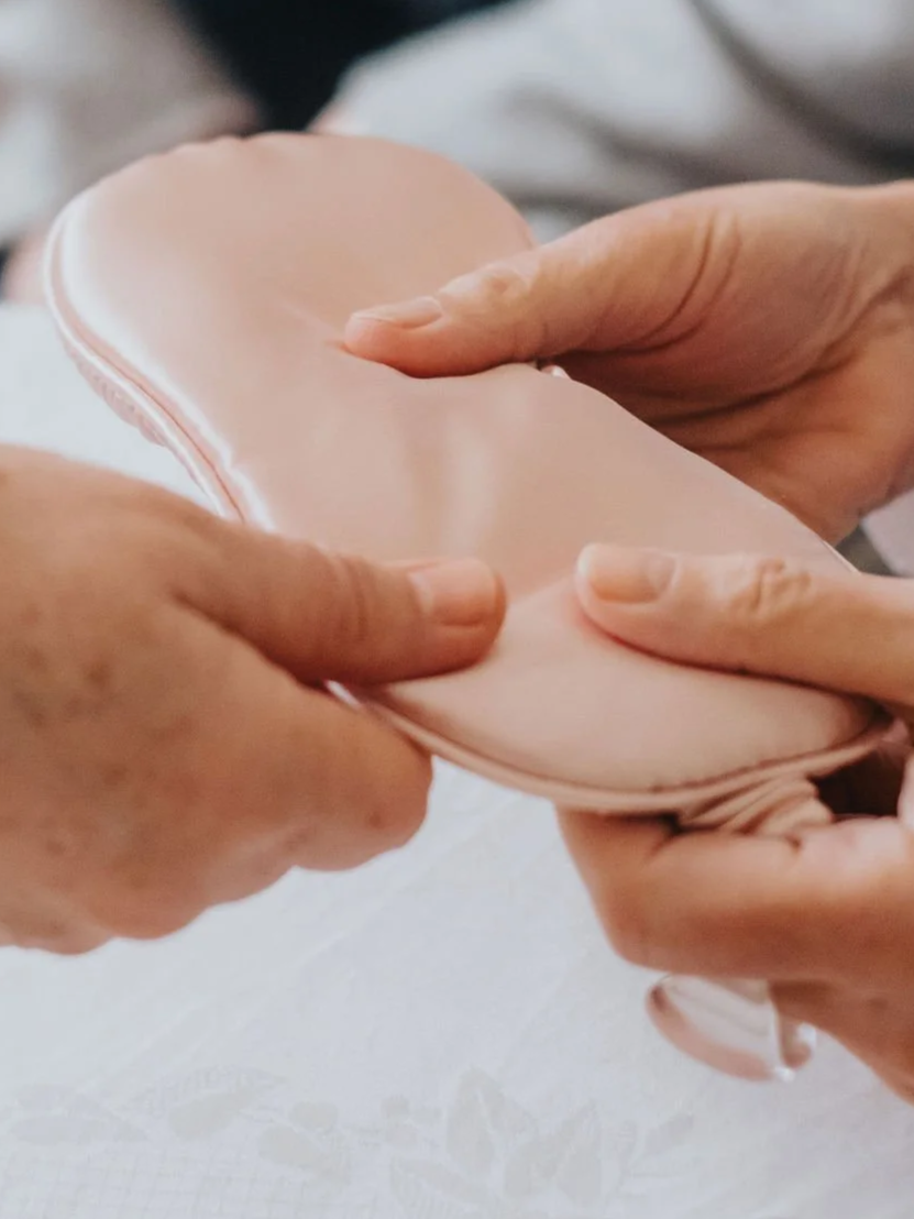 Deux mains manipulant une prothèse en silicone de couleur pêche.
