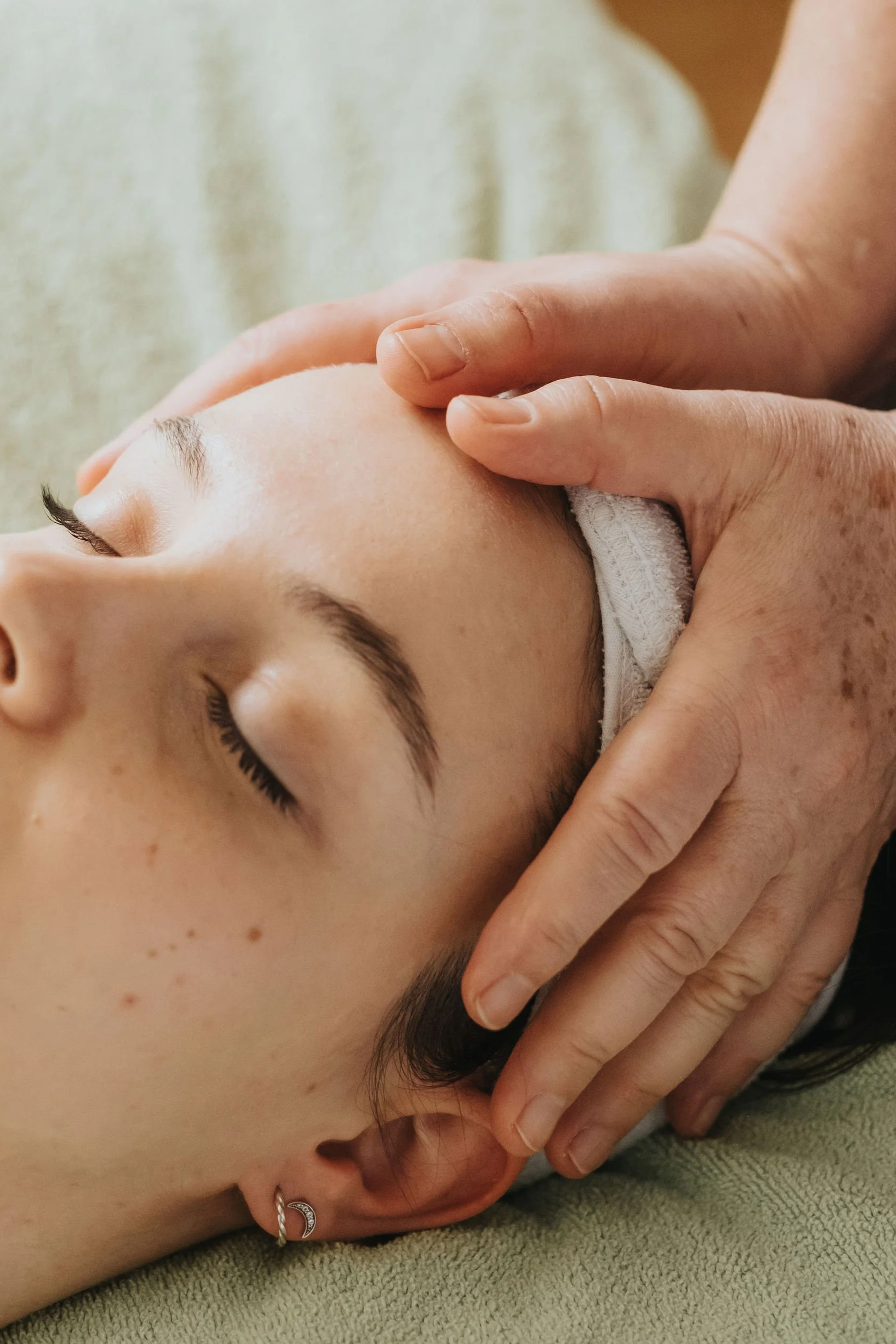 Massage du cuir chevelu : mains de la praticienne sur le front et le haut du crâne d'une cliente.
