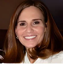 Close-up of a smiling woman with brown hair and earrings