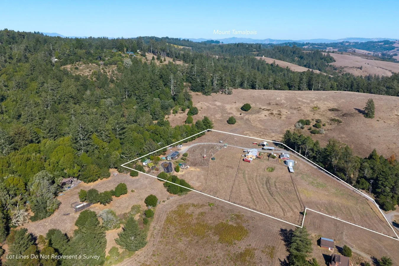 Aerial view of a rural property outlined with white lines, featuring several buildings, trees, and a large open field, with forested hills in the background and Mount Tamalpais labeled in the distance.