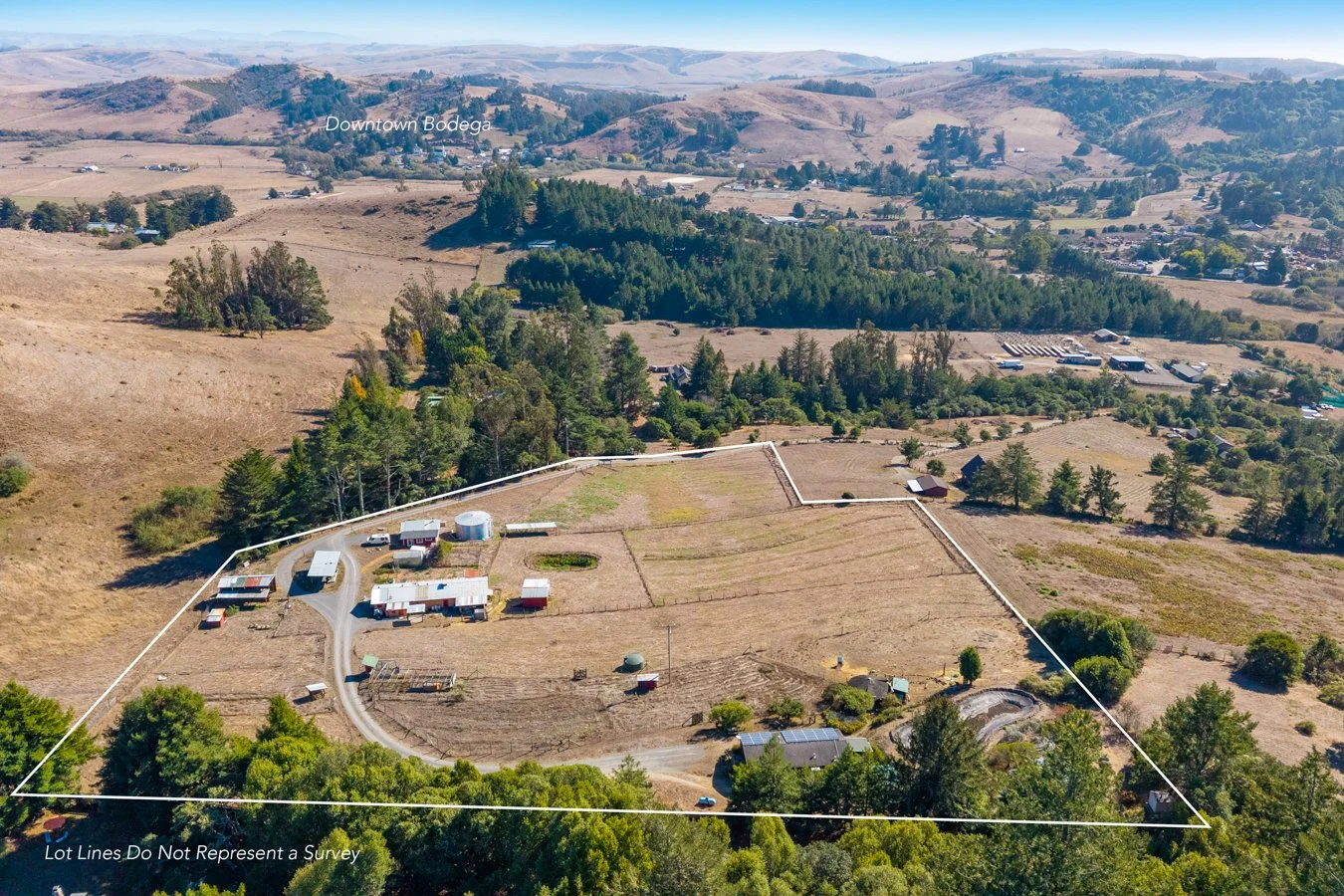 Aerial view of a rural farm with buildings, fields, and trees, surrounded by rolling hills, with the label 'Downtown Bodega.'