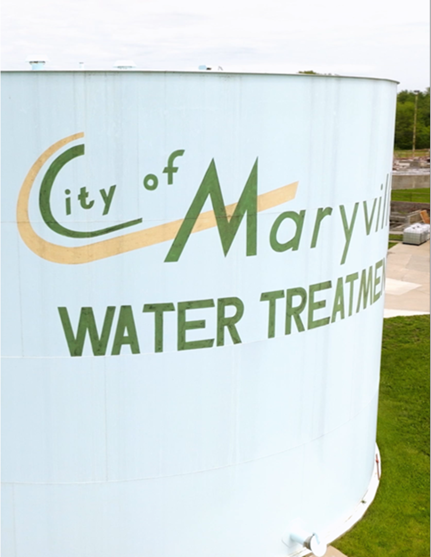 Water tower with sign reading 'City of Maryville Water Treatment' in green and beige letters.