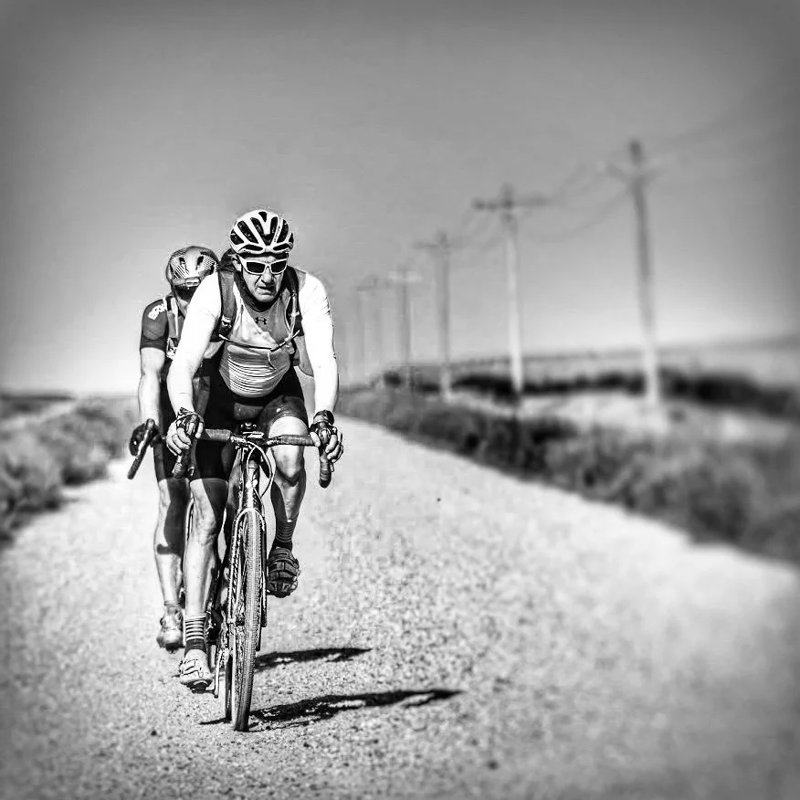 Two cyclists riding on a gravel road under power lines, fueled by nutrition coaching in Missoula