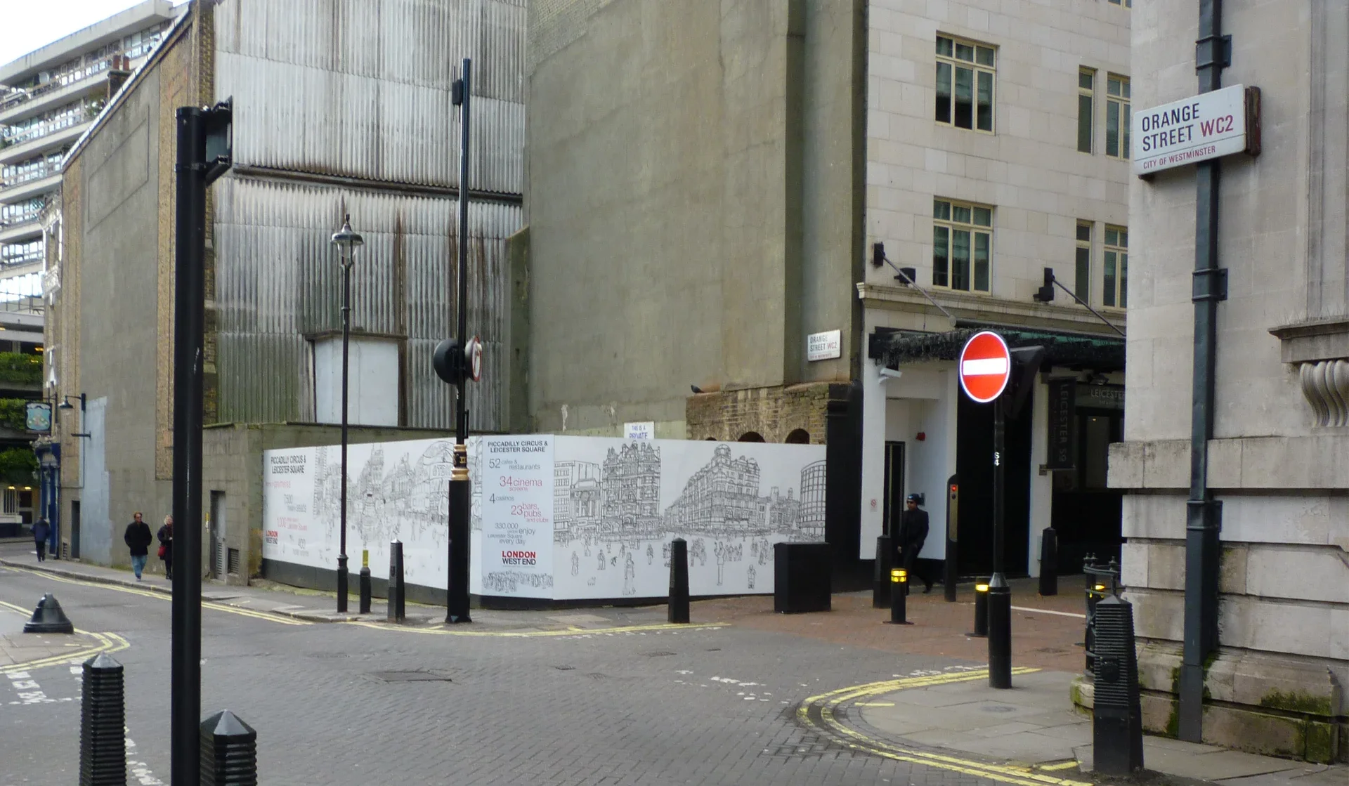 Wide contextual street view showing the scale of the site-specific hoarding installation in London's West End.